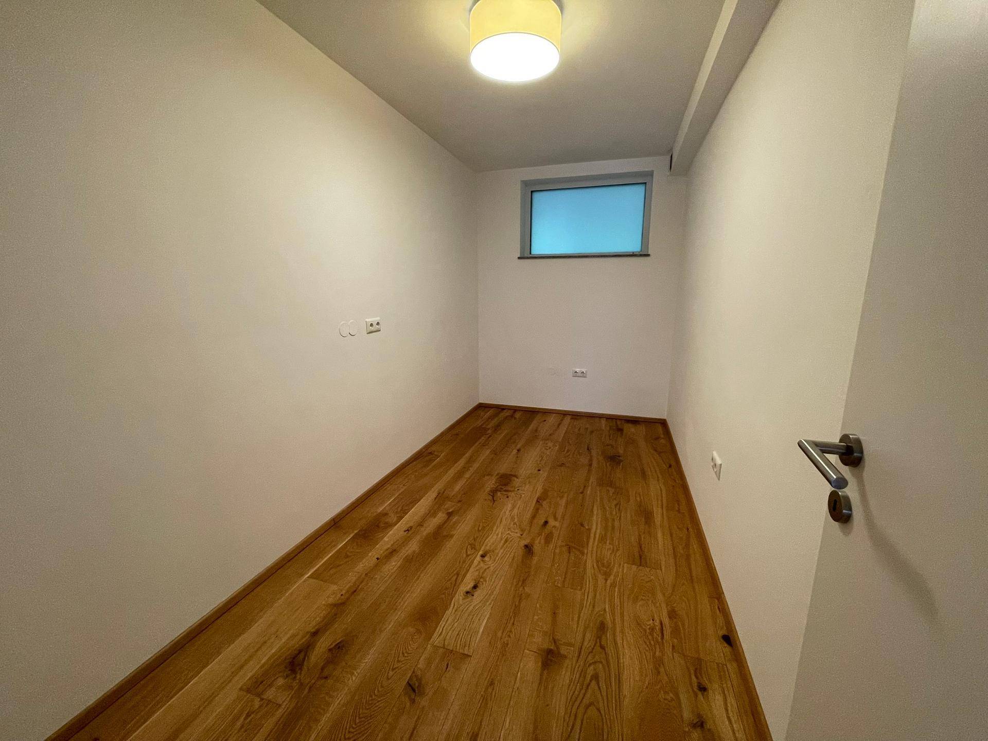 Leeres Arbeitszimmer mit Holzboden und einem Fenster, bereit zur individuellen Gestaltung.