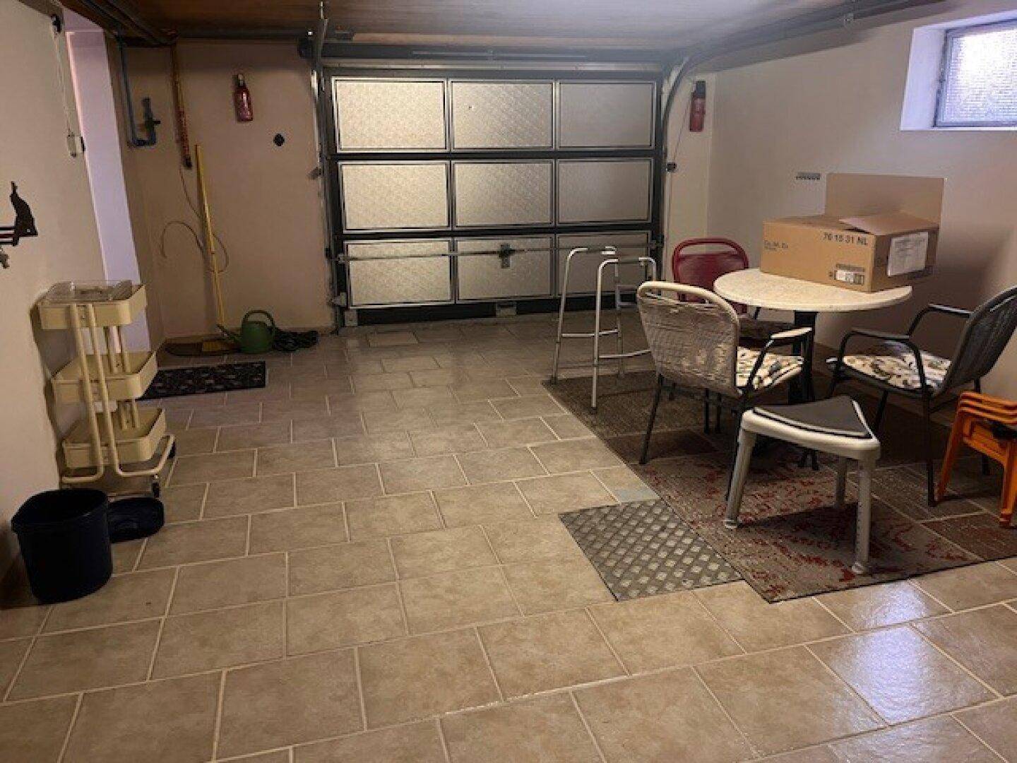 Geräumige Garage im Untergeschoss mit Fliesenboden und Platz für Fahrzeuge oder Lagerung.