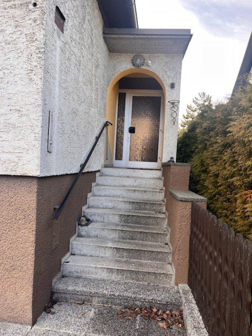 Hauseingang mit Außentreppe, Handlauf und überdachtem Bereich.