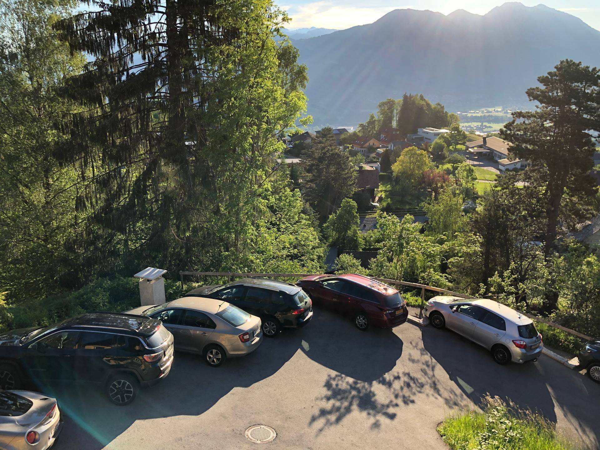 Außenparkplatz mit mehreren Fahrzeugen und einem weiten Blick auf die umliegende Berglandschaft.