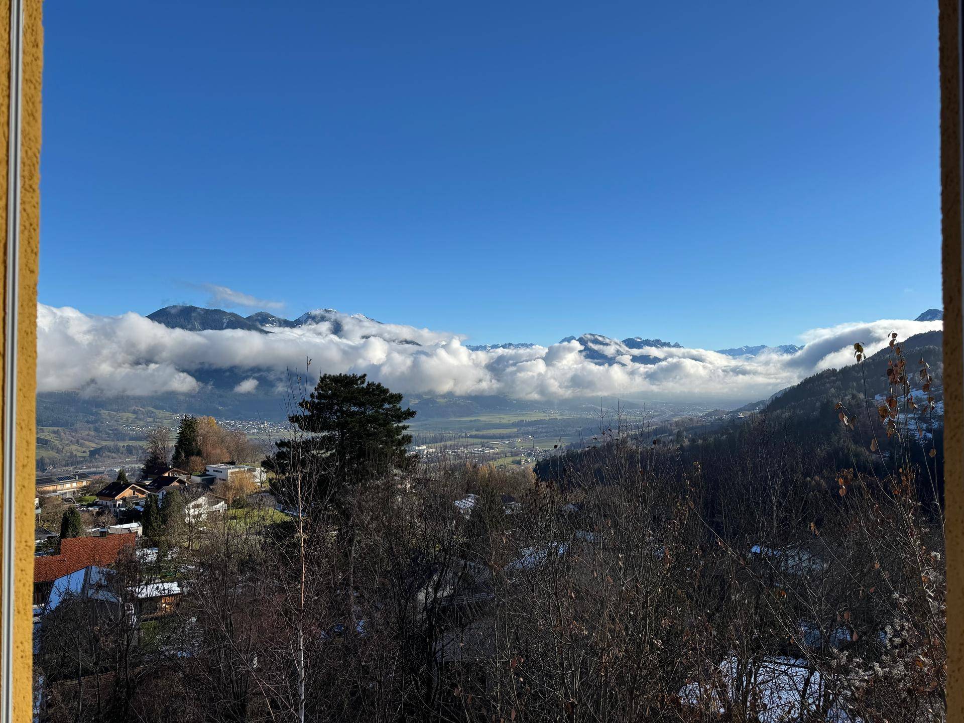 Atemberaubender Bergblick mit Wolken über den Gipfeln und weitem Talblick an einem sonnigen Tag.
