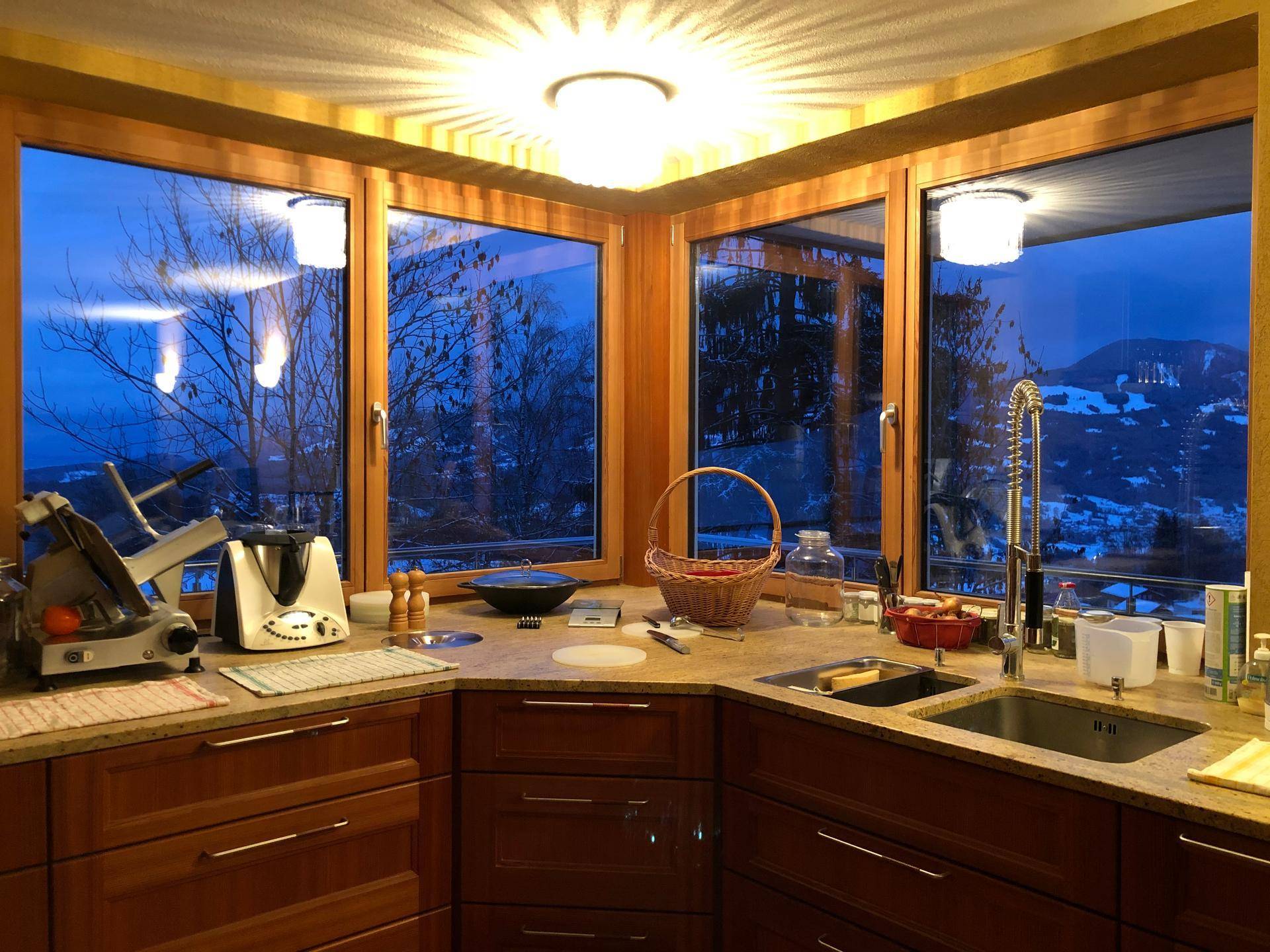 Gemütliche Küche mit Holzelementen und großen Fenstern, die einen weiten Blick auf die verschneite Landschaft bieten.