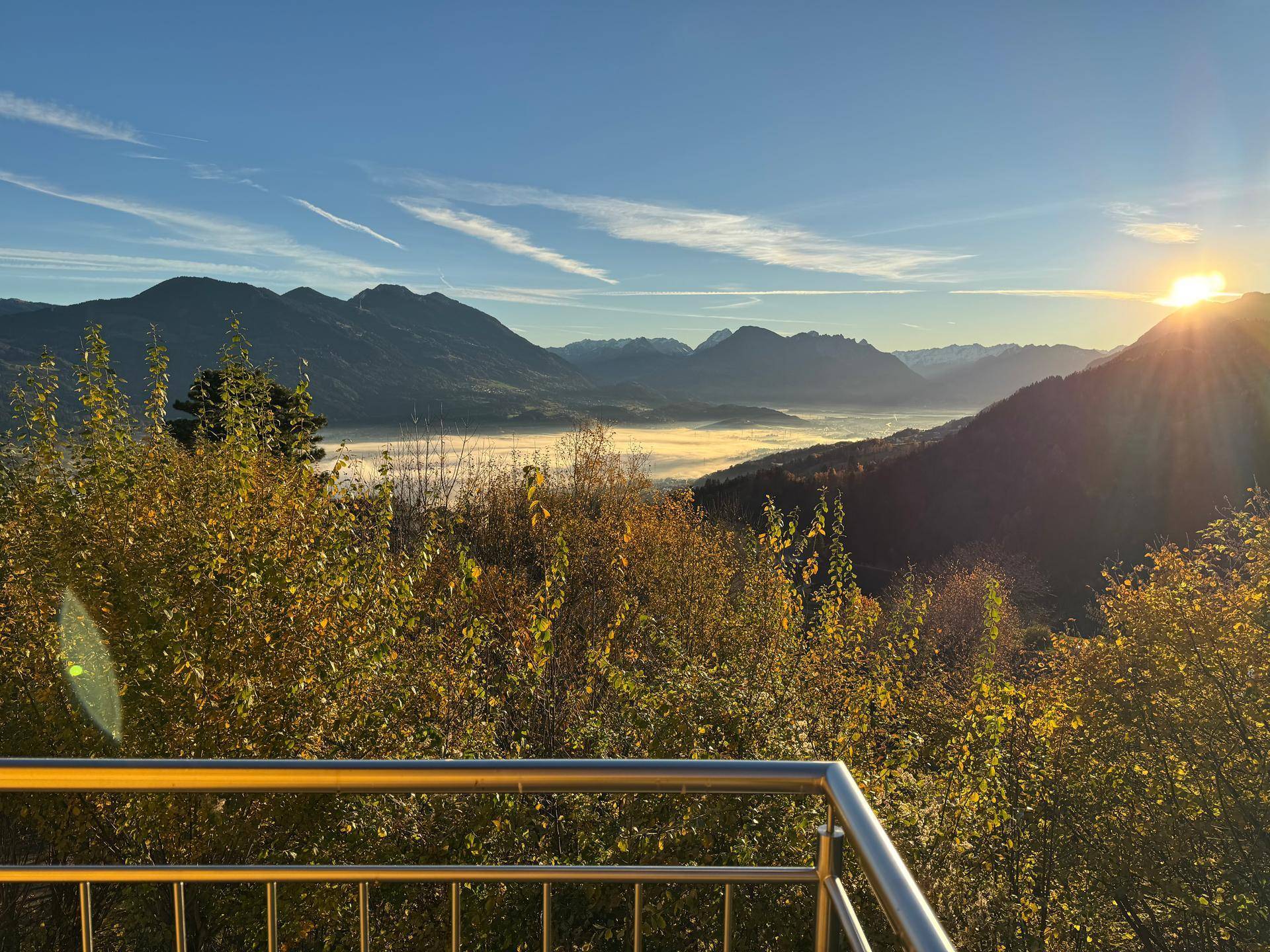 Atemberaubender Sonnenaufgang über einer nebelverhangenen Berglandschaft, gesehen von einem Balkon.
