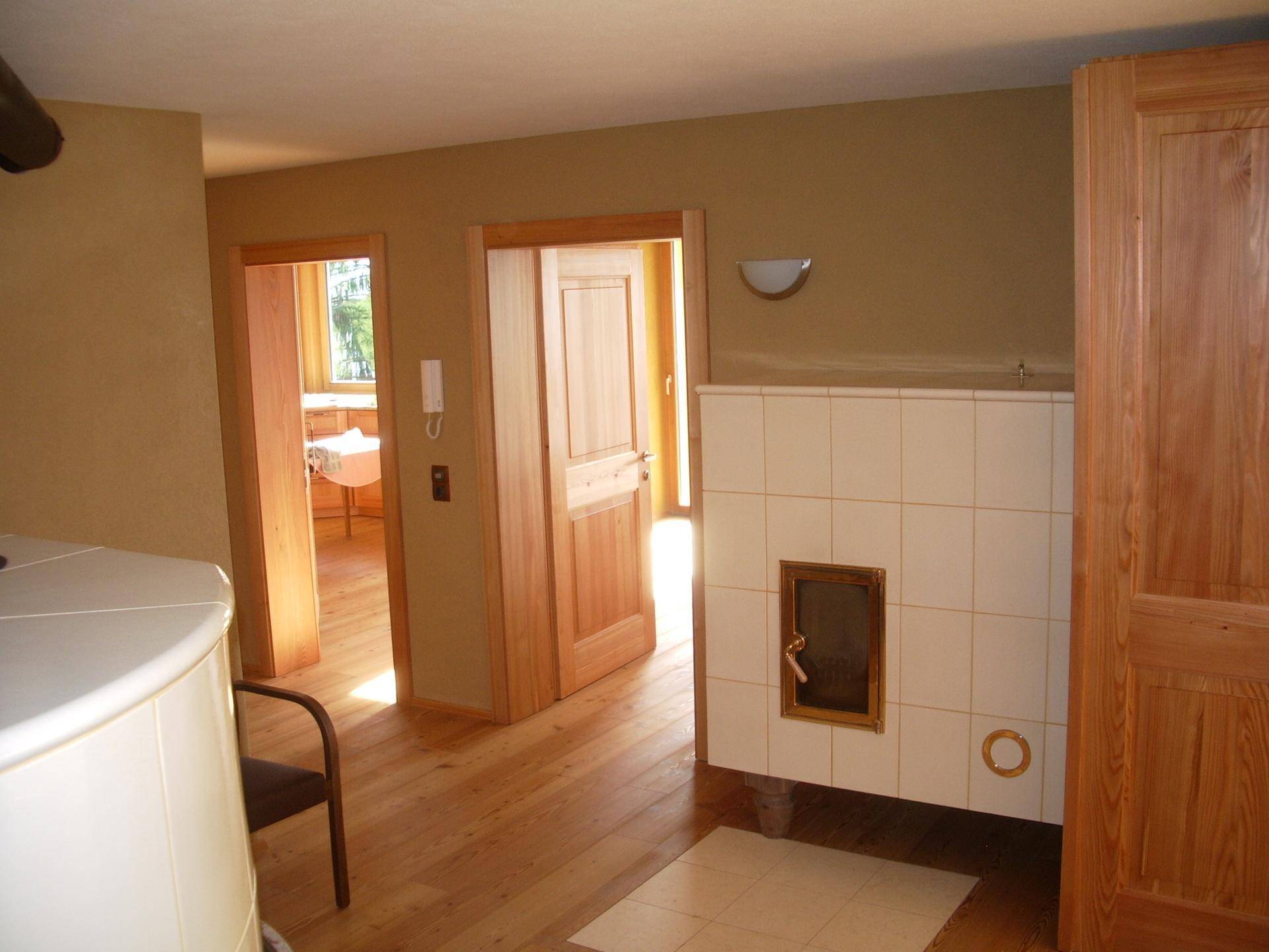 Heller Flur mit Holzboden und einem traditionellen Kachelofen, der Wärme und Gemütlichkeit spendet.