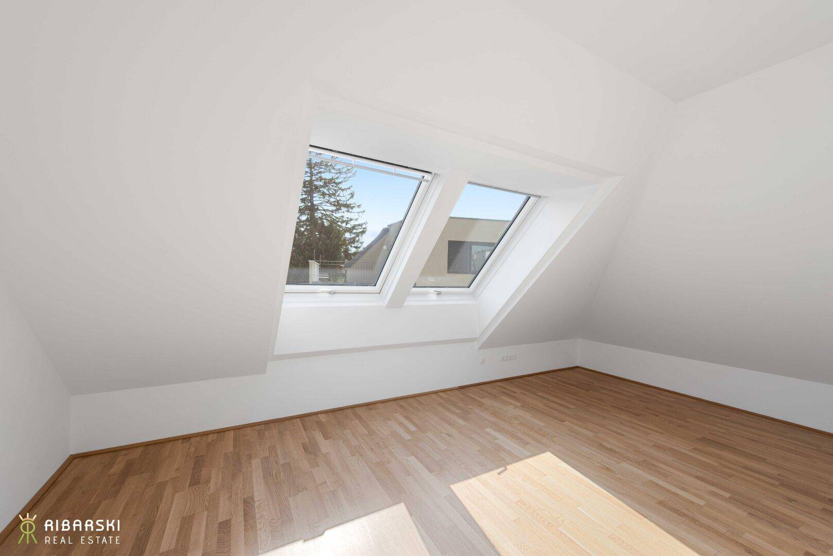 Heller Raum im Dachgeschoss mit Holzboden und zwei Dachfenstern, ideal für Schlaf- oder Arbeitszimmer.