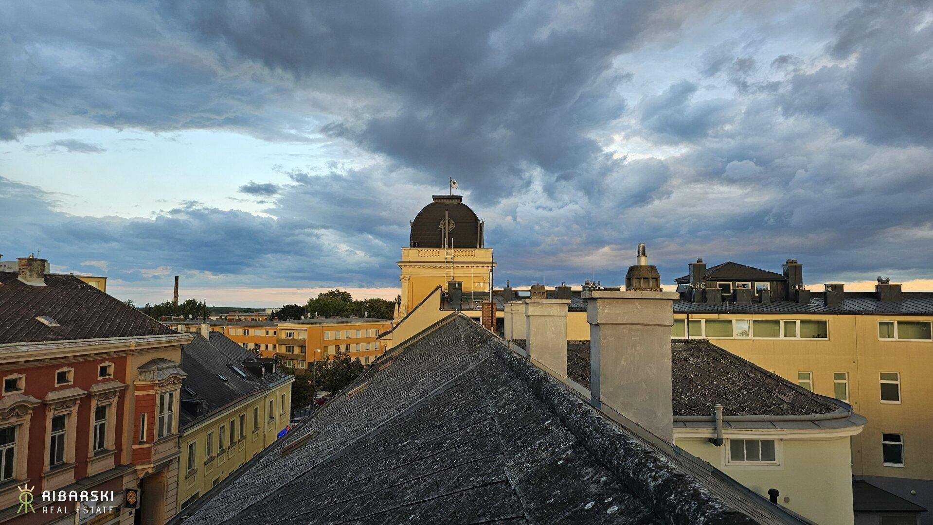 Panoramablick über die Dächer der Stadt mit einem markanten Kuppelgebäude am Horizont.