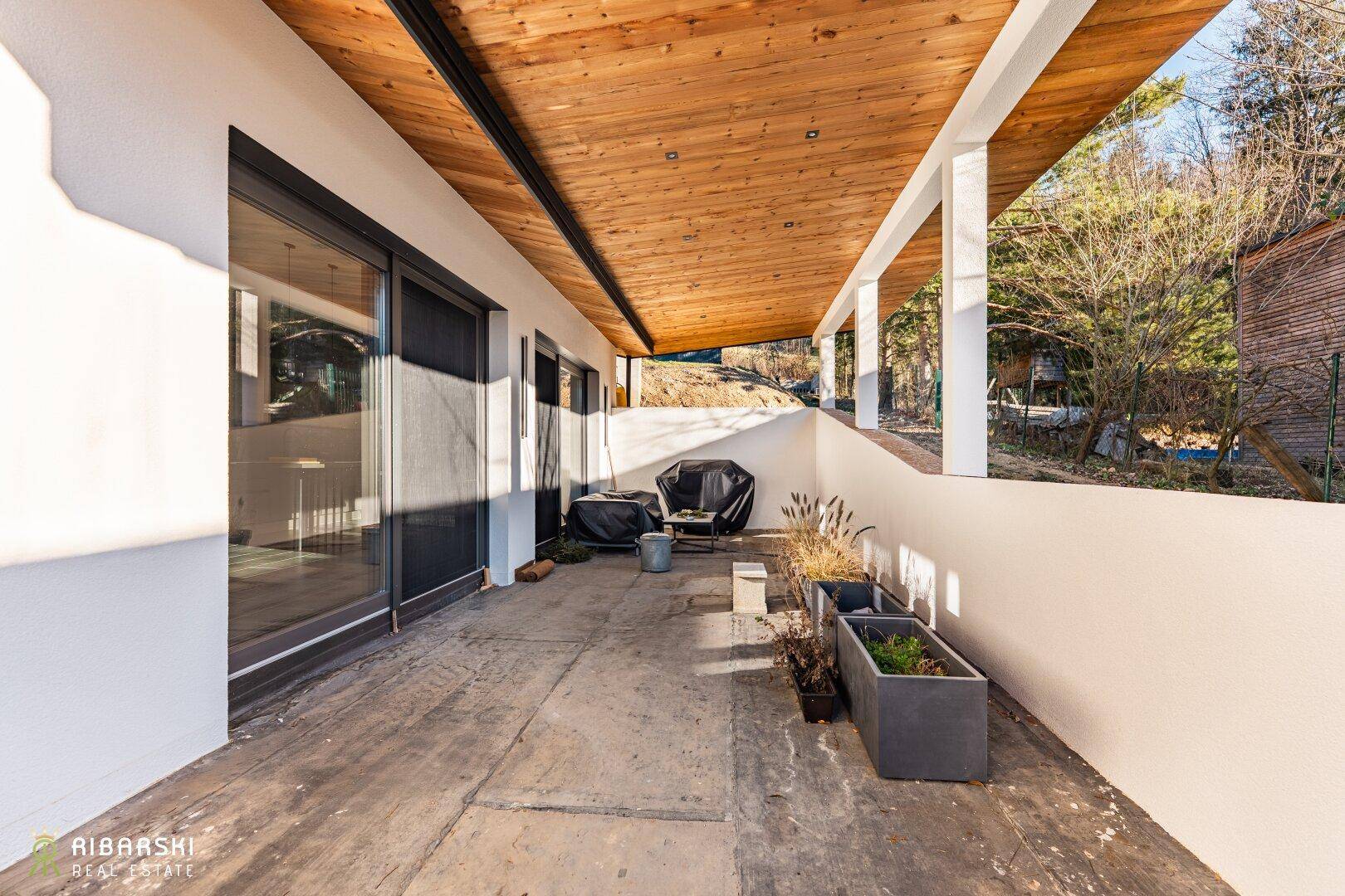 Überdachte Terrasse mit Holzdach, Grillbereich und Blick ins Grüne, ideal für Entspannung.