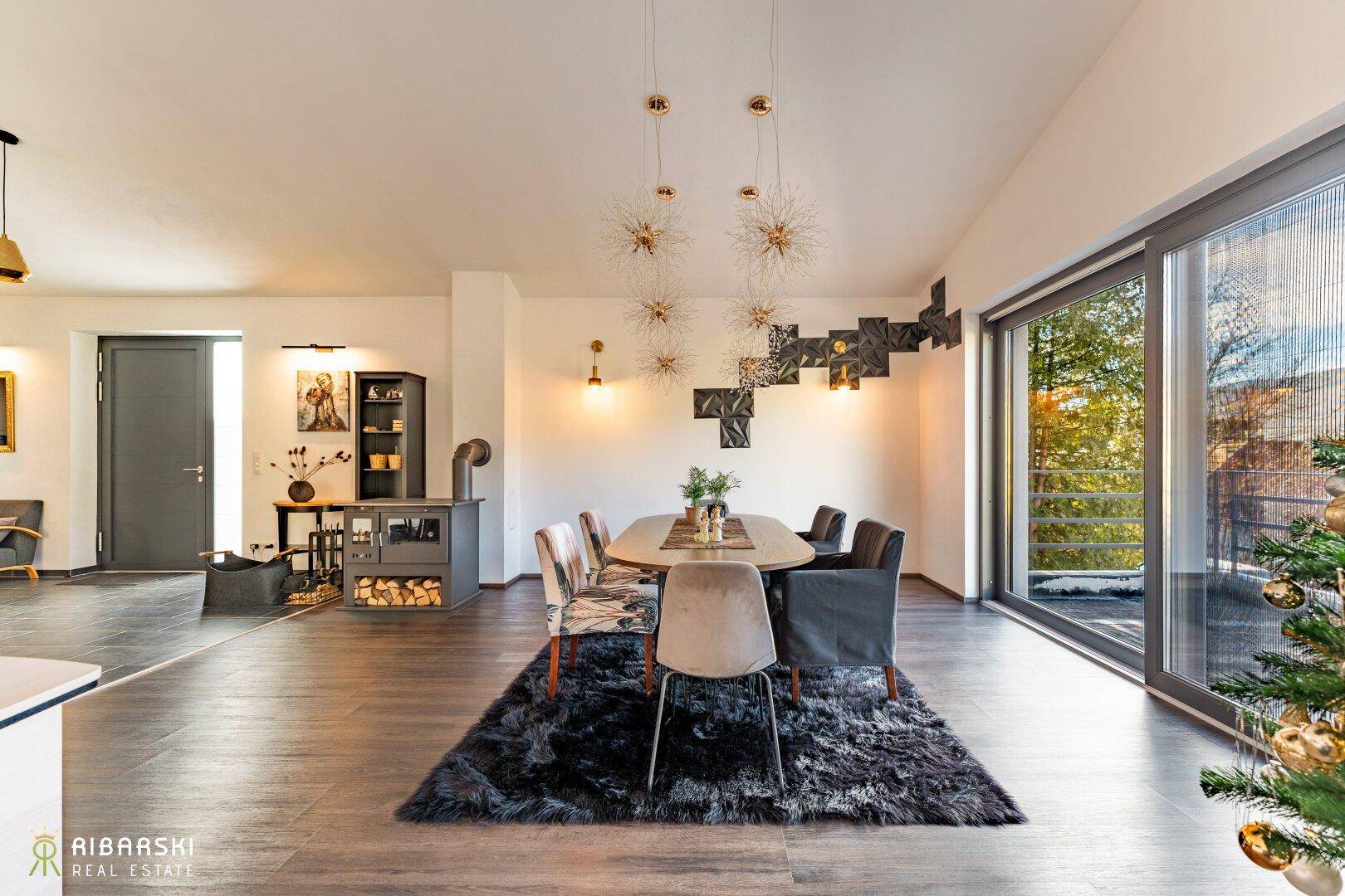 Eleganter Essbereich mit großem Tisch, Holzboden und einem modernen Kaminofen.