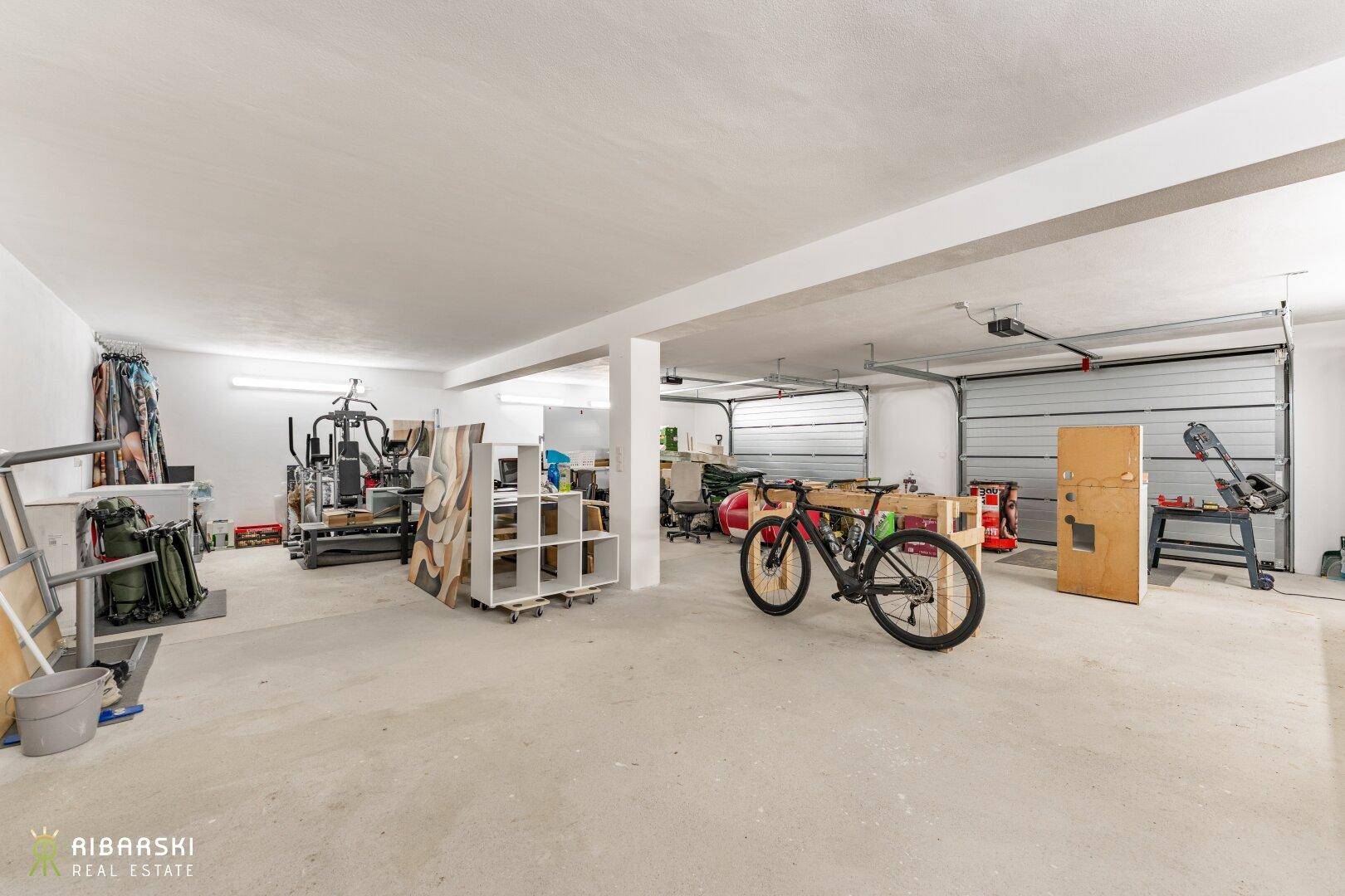 Geräumige Garage mit zwei Toren, die auch als Fitnessbereich genutzt wird.
