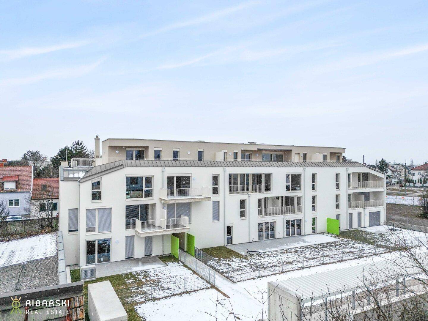 Gesamtansicht einer modernen Wohnanlage mit mehreren Etagen und umliegender Landschaft.