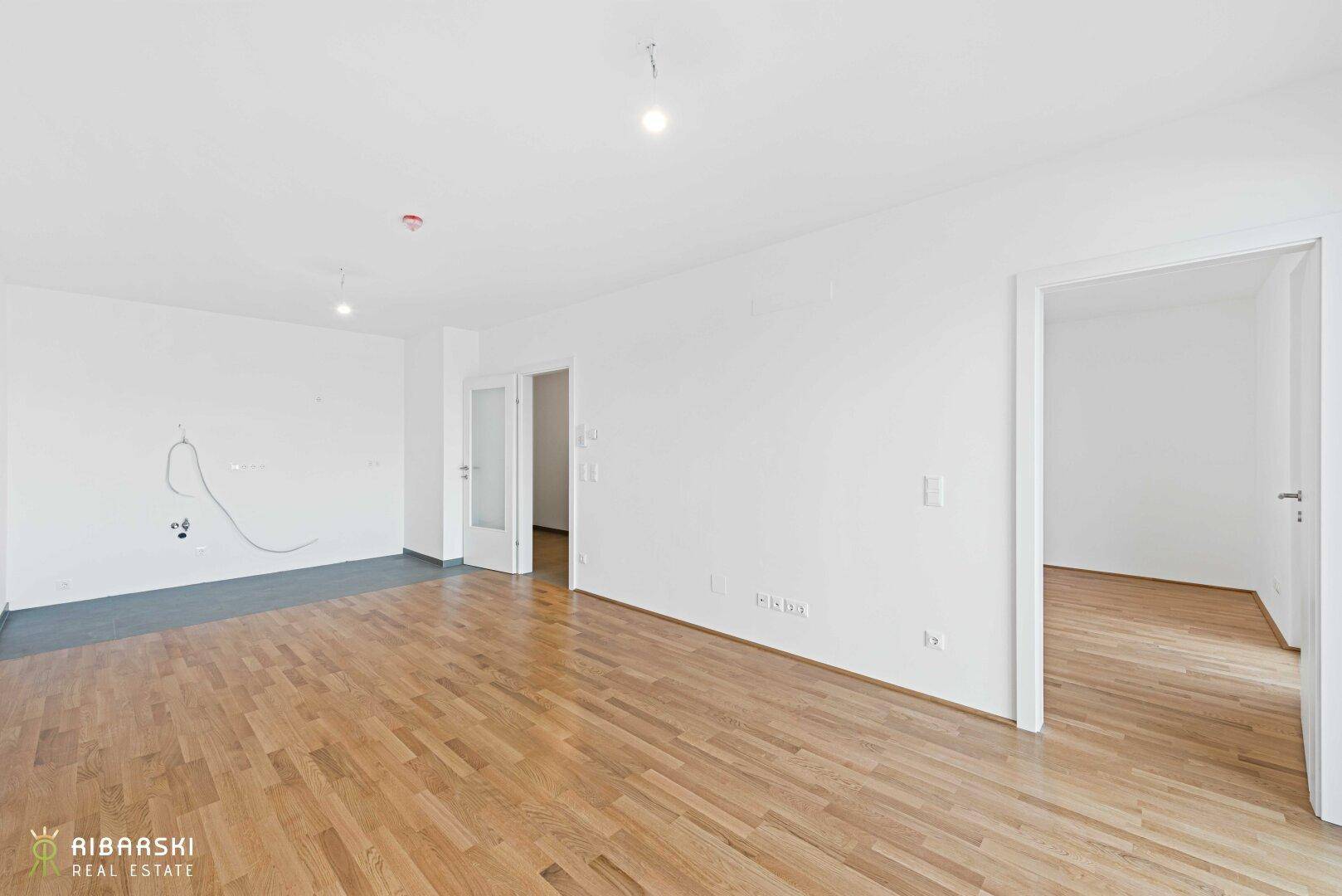 Geräumiges Wohnzimmer mit Parkettboden und mehreren Türen zu angrenzenden Räumen.