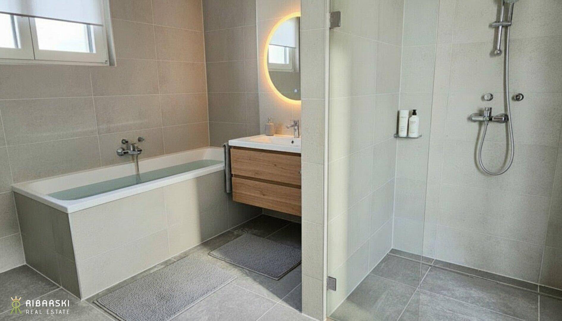 Modernes Badezimmer mit Badewanne, Dusche, Holzwaschtisch und beleuchtetem Spiegel.