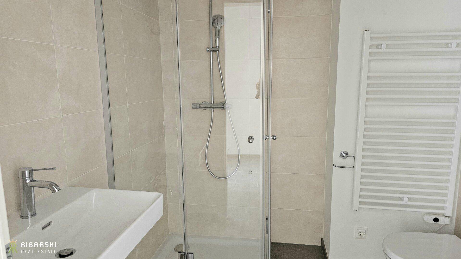 Modernes Badezimmer mit begehbarer Dusche, eleganten Fliesen und beheiztem Handtuchhalter.