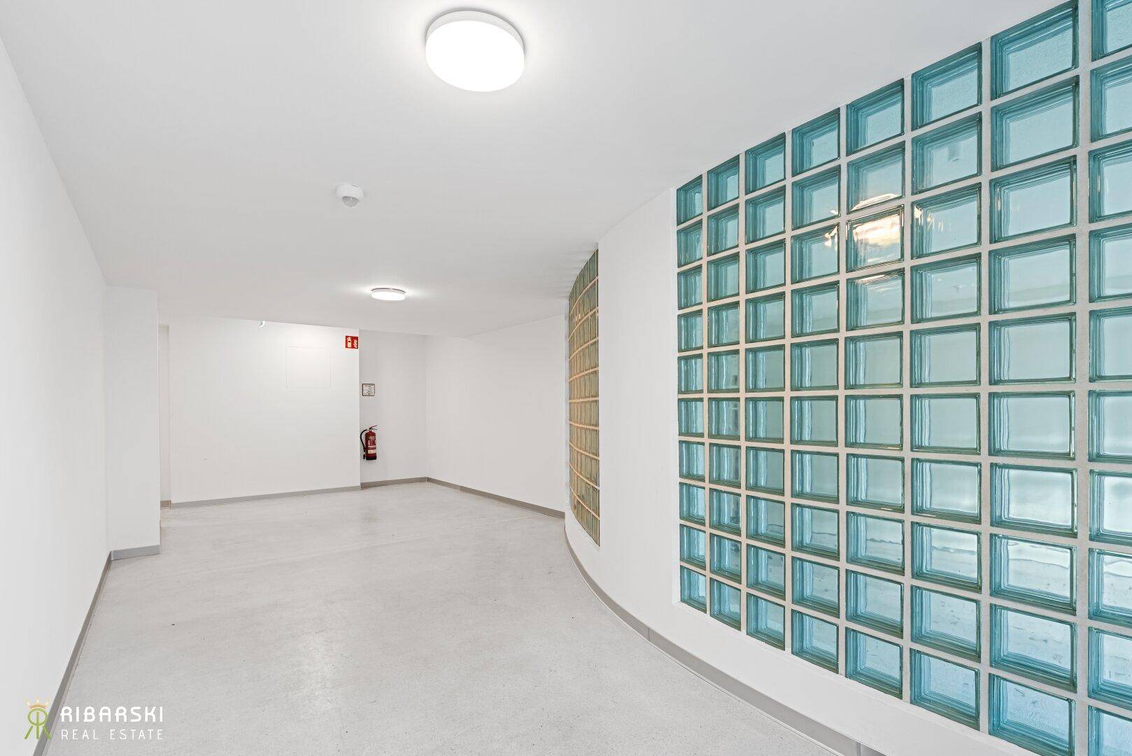 Heller Flur mit dekorativer Glasbausteinwand und schlichtem Design im Eingangsbereich des Gebäudes.