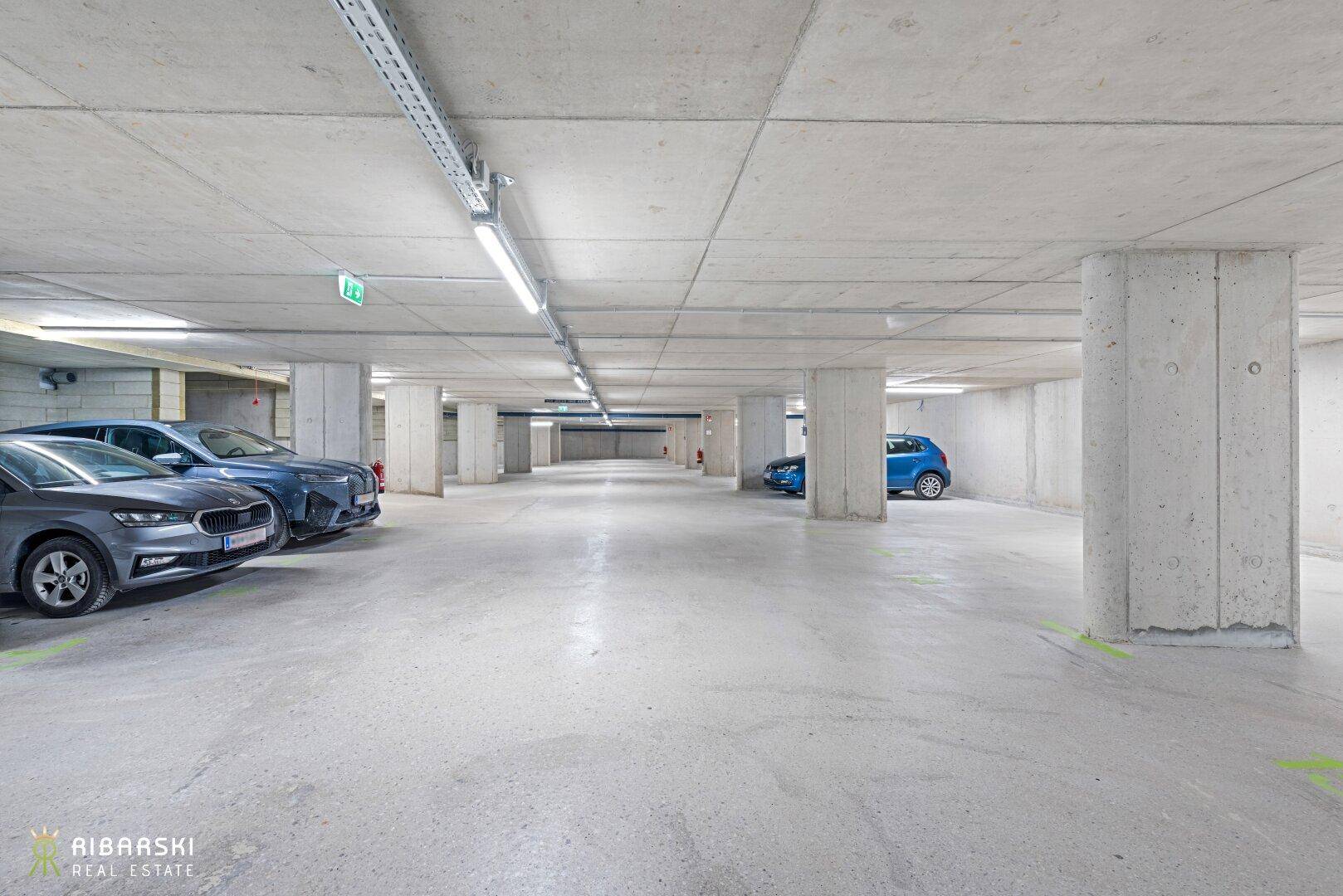 Geräumige Tiefgarage mit mehreren Stellplätzen und Betonwänden sowie Deckenbeleuchtung.