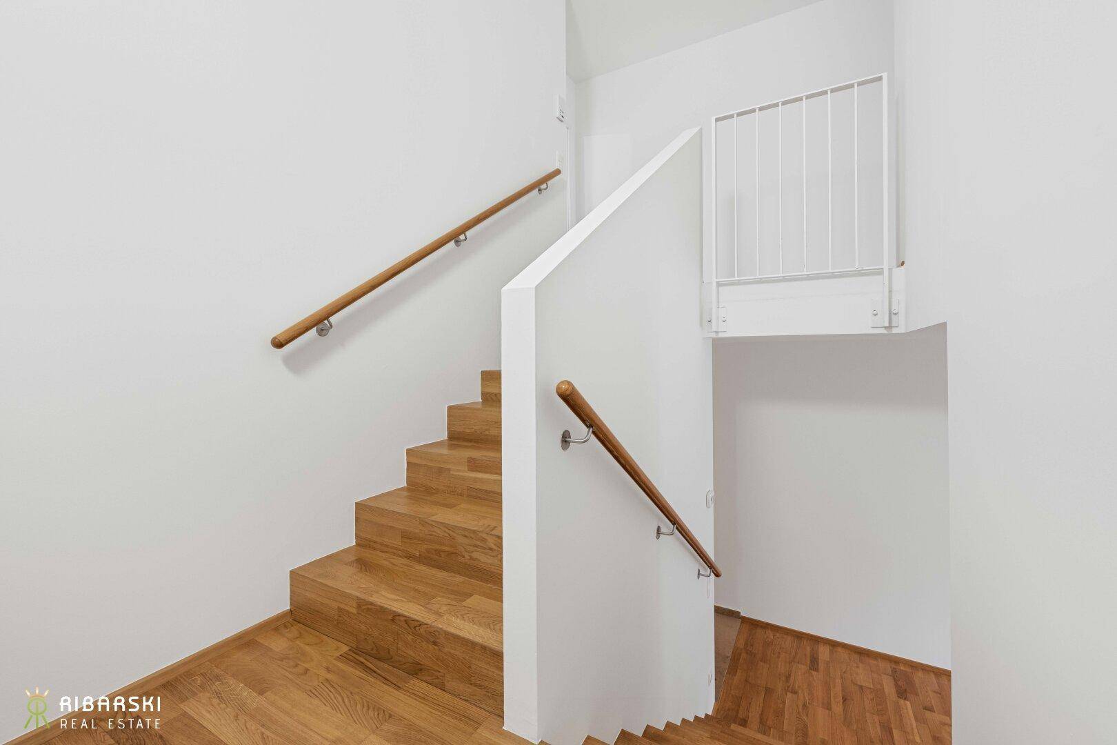 Holztreppe mit Holzgeländer und Kinderschutzgitter, führt in die oberen Etagen.