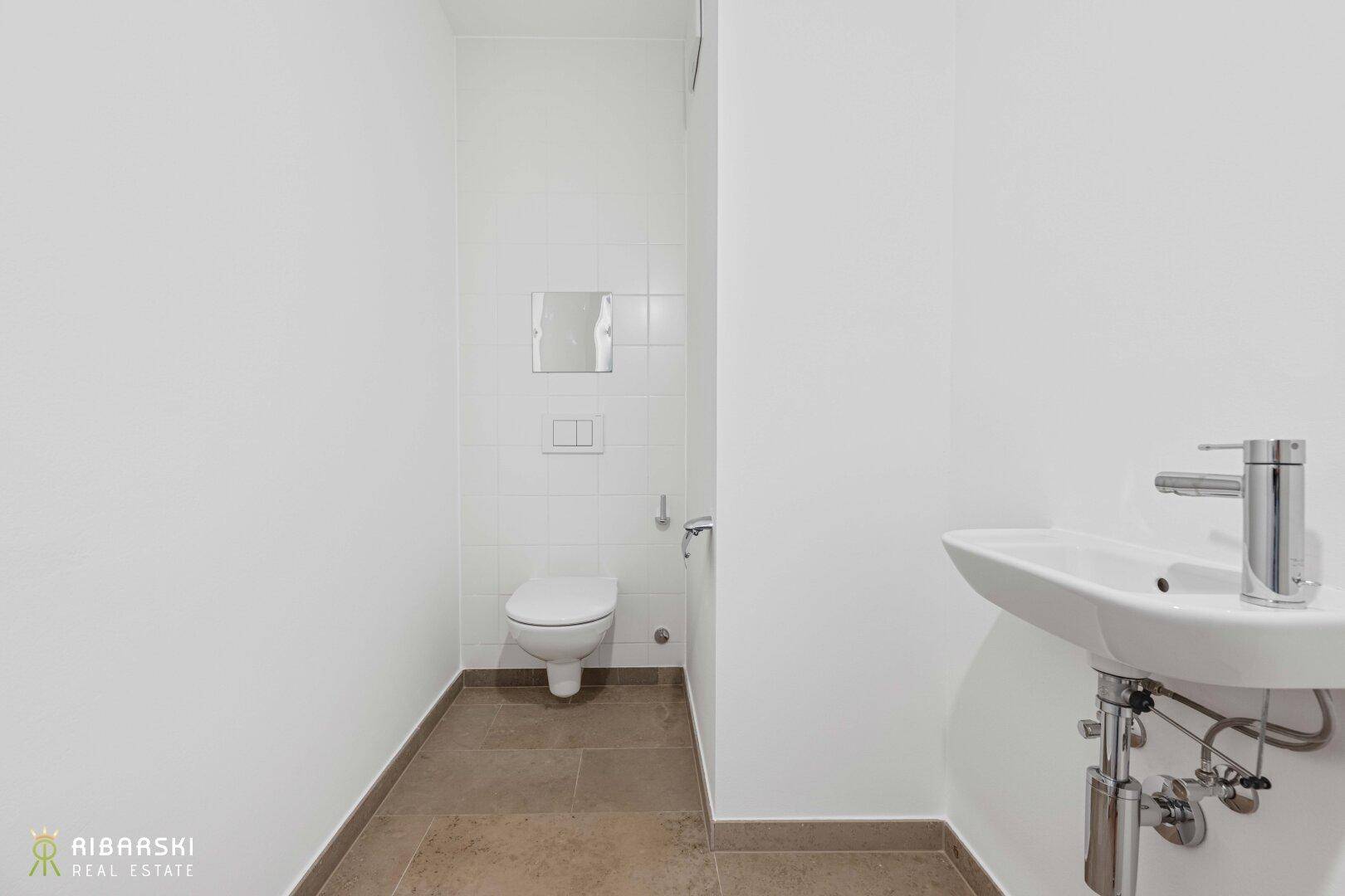 Modernes Gäste-WC mit wandhängendem WC und kleinem Waschbecken.