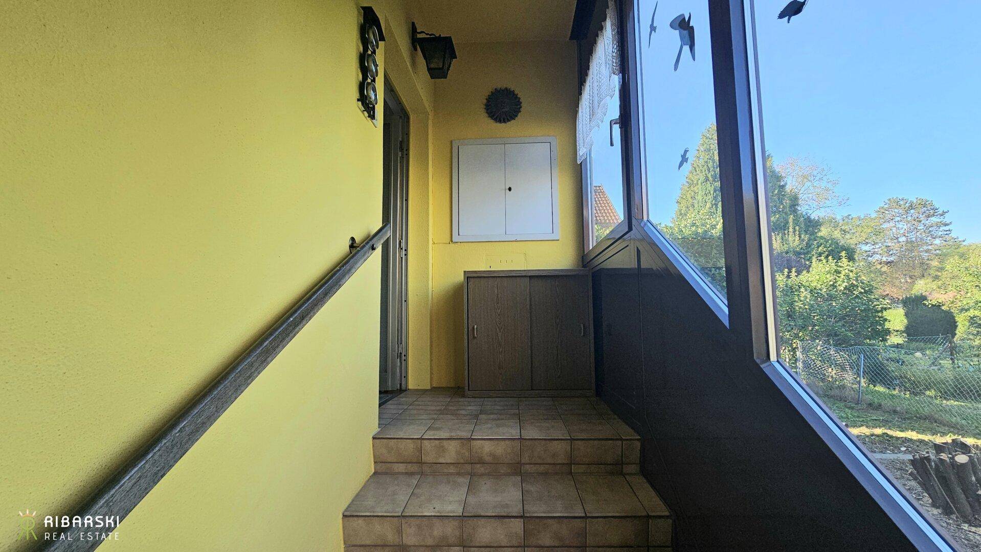 Verglaster Eingangsbereich mit Fliesenboden und Blick ins Grüne, als Wintergarten nutzbar.