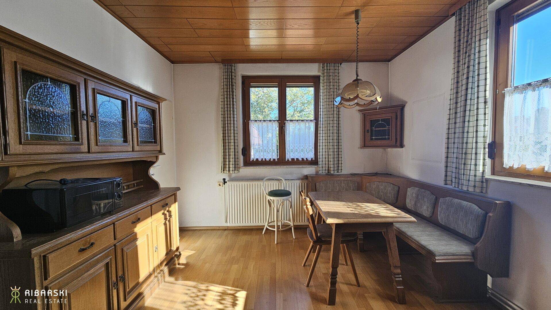 Gemütlicher Essbereich mit Holztäfelung an Decke und Wänden, traditionellen Möbeln und Fensterblick.