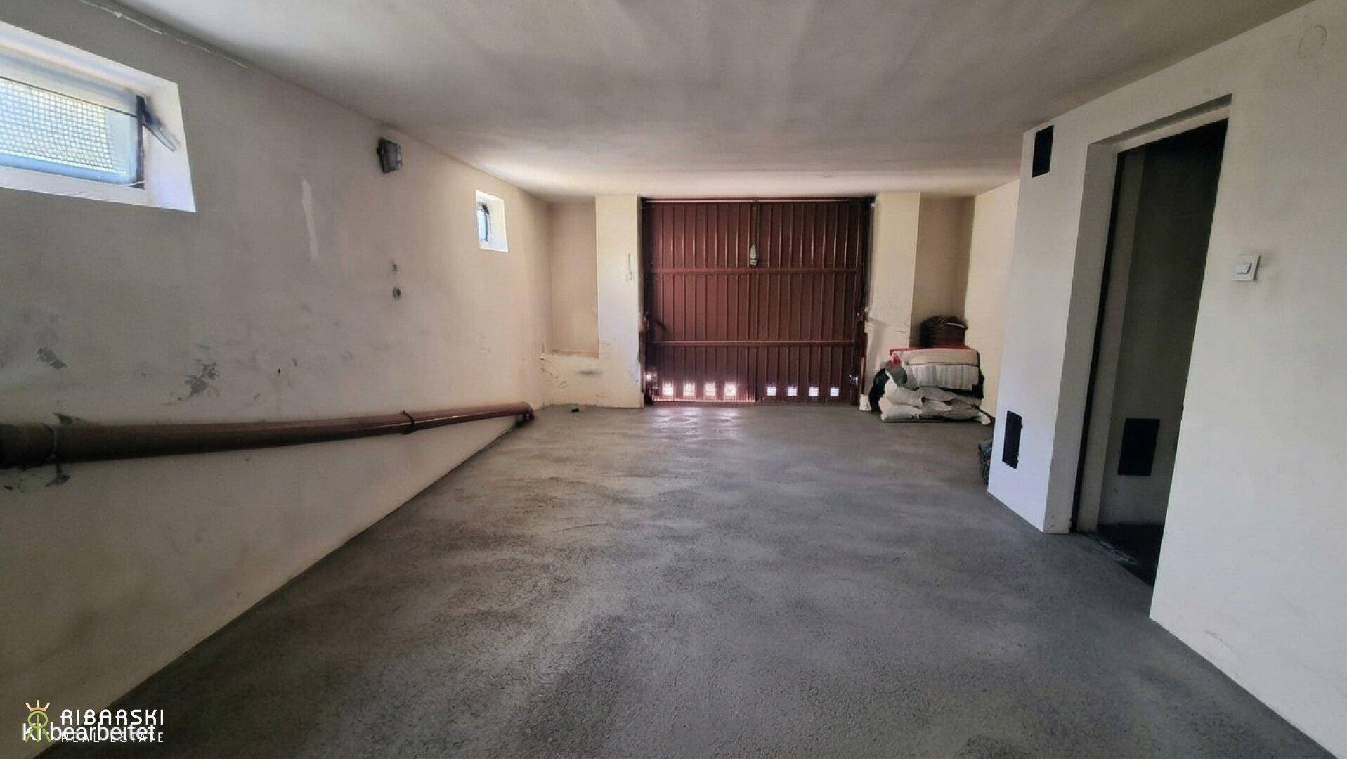 Geräumige Garage im Untergeschoss mit Betonboden und großem Tor, ideal für Fahrzeuge.