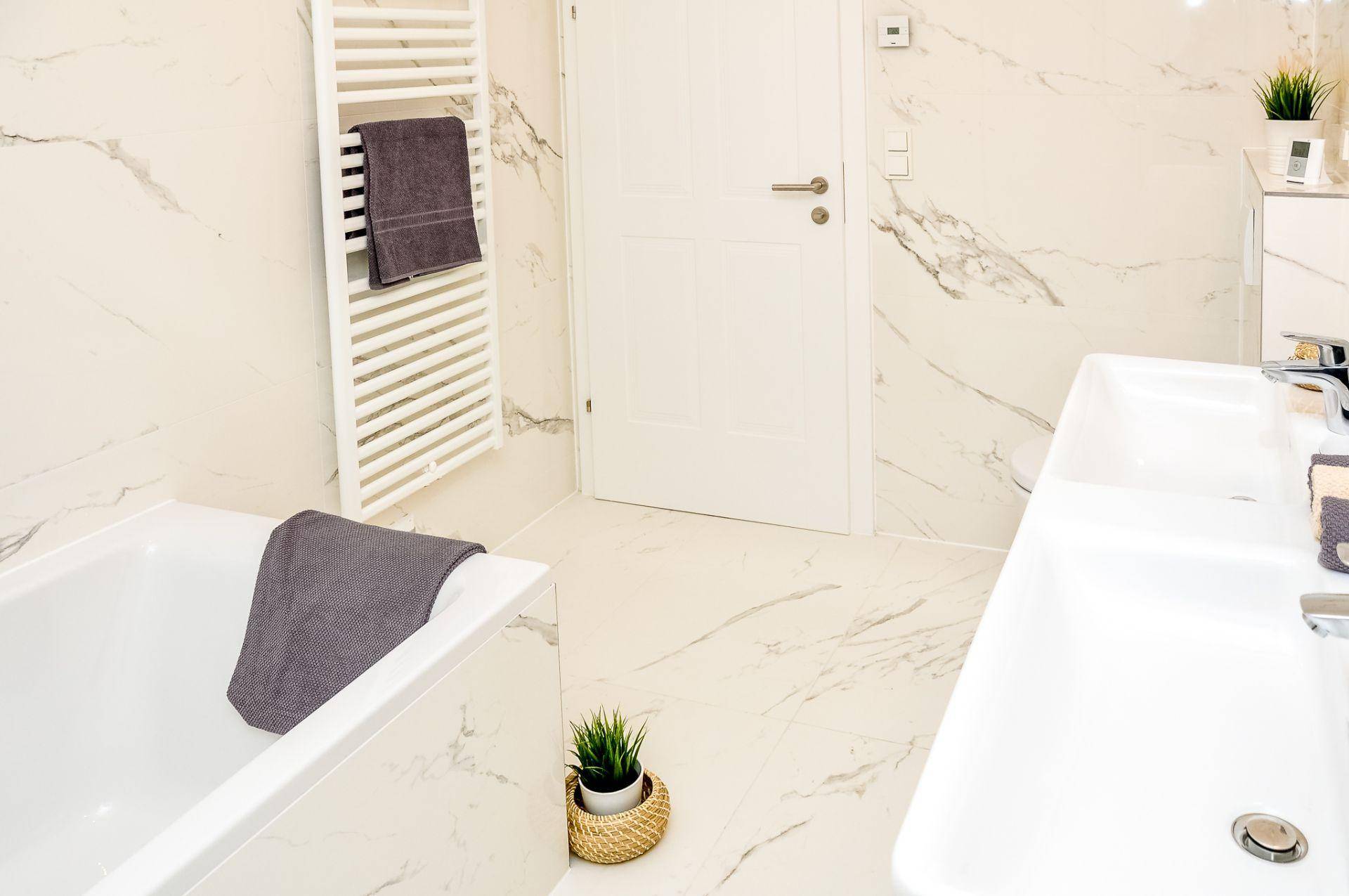 Modernes Badezimmer mit Doppelwaschbecken, Badewanne und beheiztem Handtuchhalter.