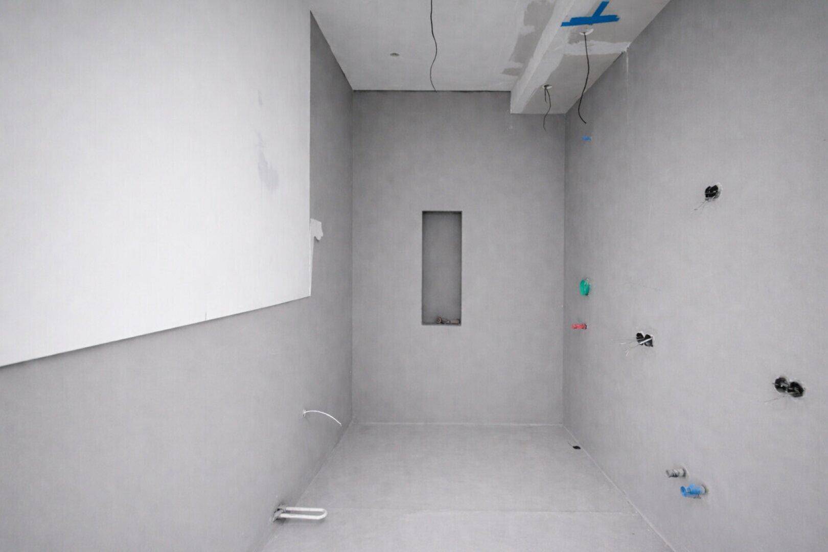 Unfertiges Badezimmer mit vorbereiteten Installationen und einer Wandnische, bereit für den Ausbau.
