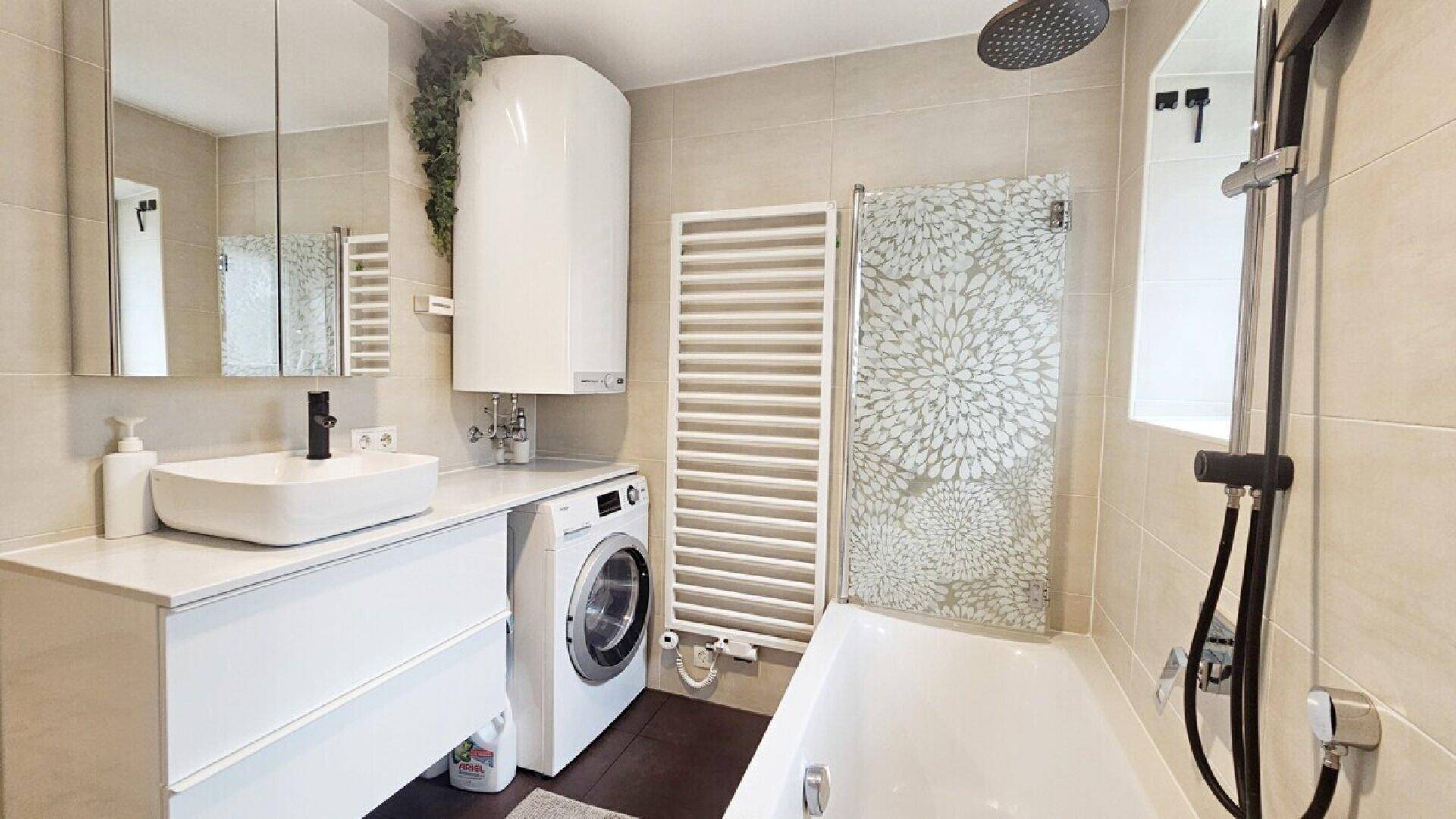 Modernes Badezimmer mit Badewanne, Regendusche, Waschmaschine und beheiztem Handtuchhalter.