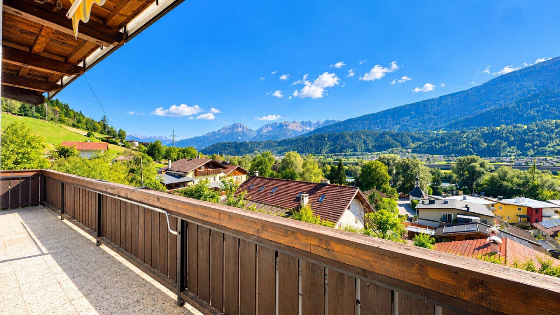 Großer Balkon mit Holzboden und Geländer, bietet einen weiten Bergblick.