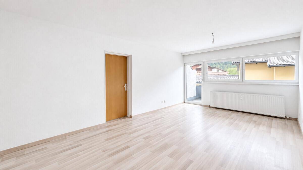 Helles Zimmer mit Laminatboden und Zugang zu einem Balkon, ideal für Wohnzwecke.