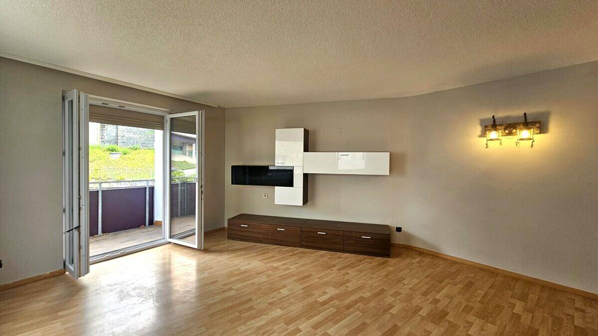 Geräumiges Wohnzimmer mit Holzboden, moderner Wanddekoration und direktem Zugang zum Balkon.