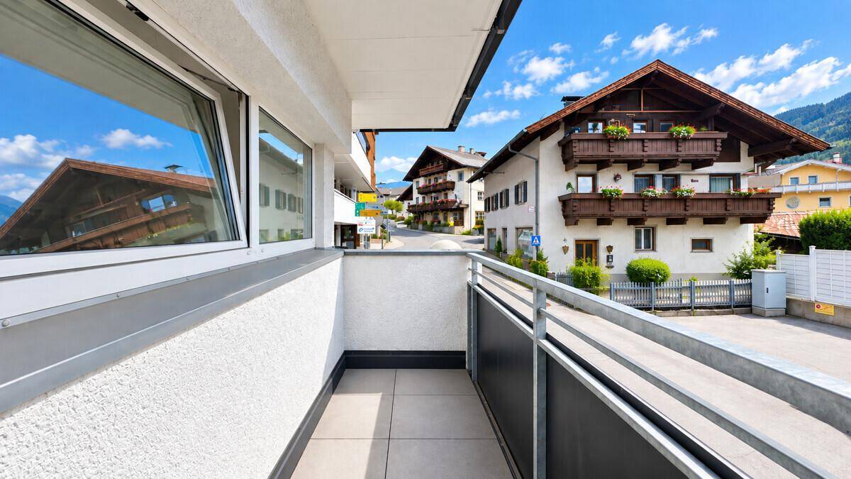 Balkon mit Fliesenboden und Bergblick, umgeben von traditionellen Häusern.