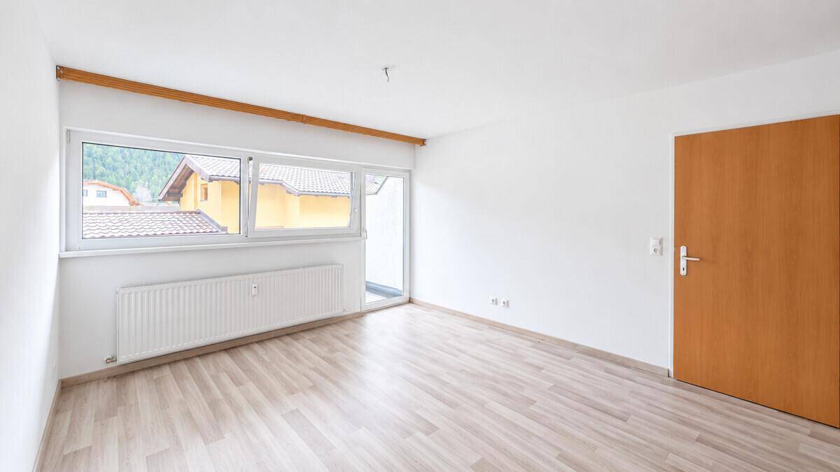 Geräumiges, helles Zimmer mit Laminatboden und großem Fensterbereich.