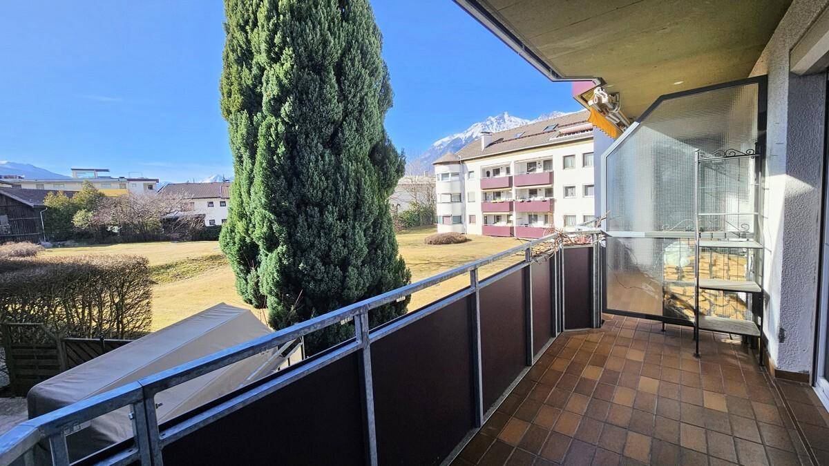 Sonniger Balkon mit Fliesenboden, Metallgeländer und einem weiten Blick auf die Berge.