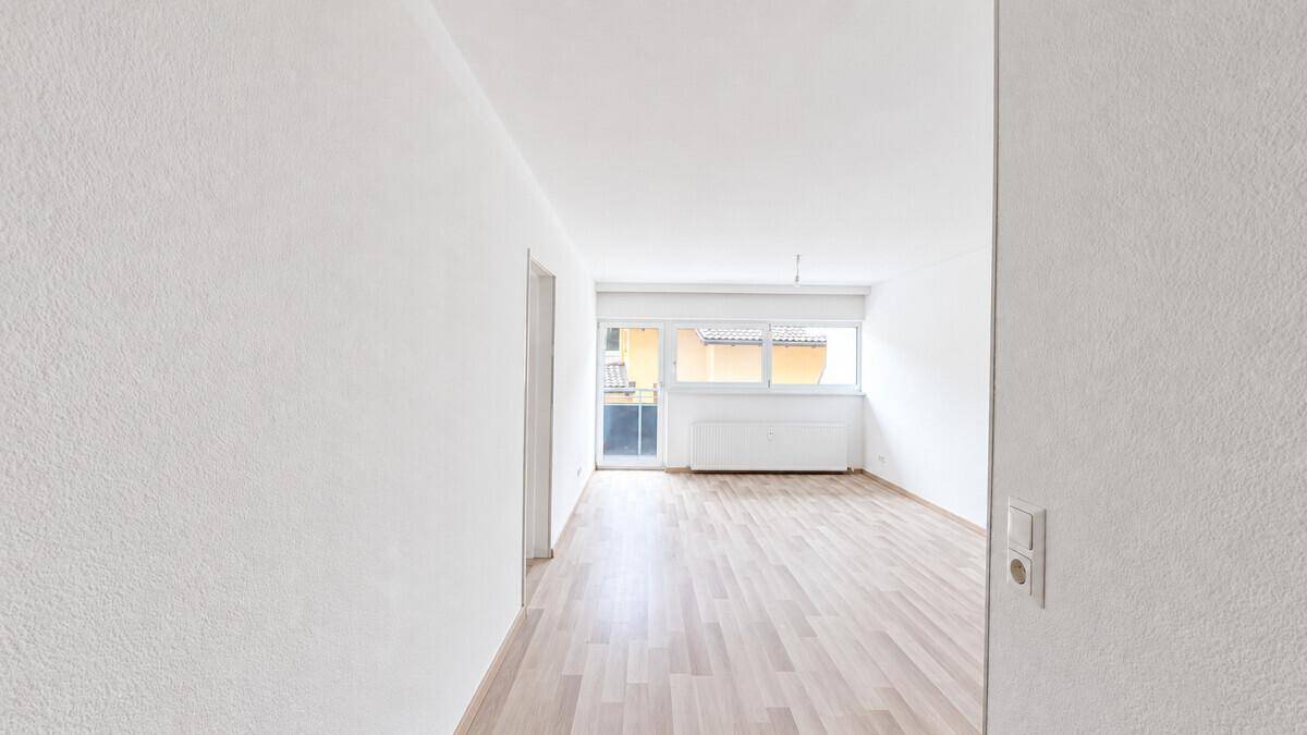 Geräumiges, helles Zimmer mit Laminatboden und Zugang zu einem Außenbereich.