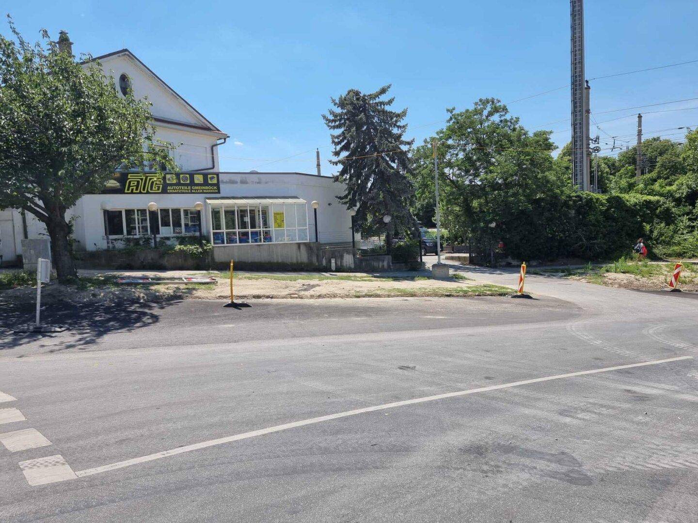 Gebäude mit AIG-Beschriftung an einer Straße, umgeben von Bäumen unter klarem blauem Himmel.
