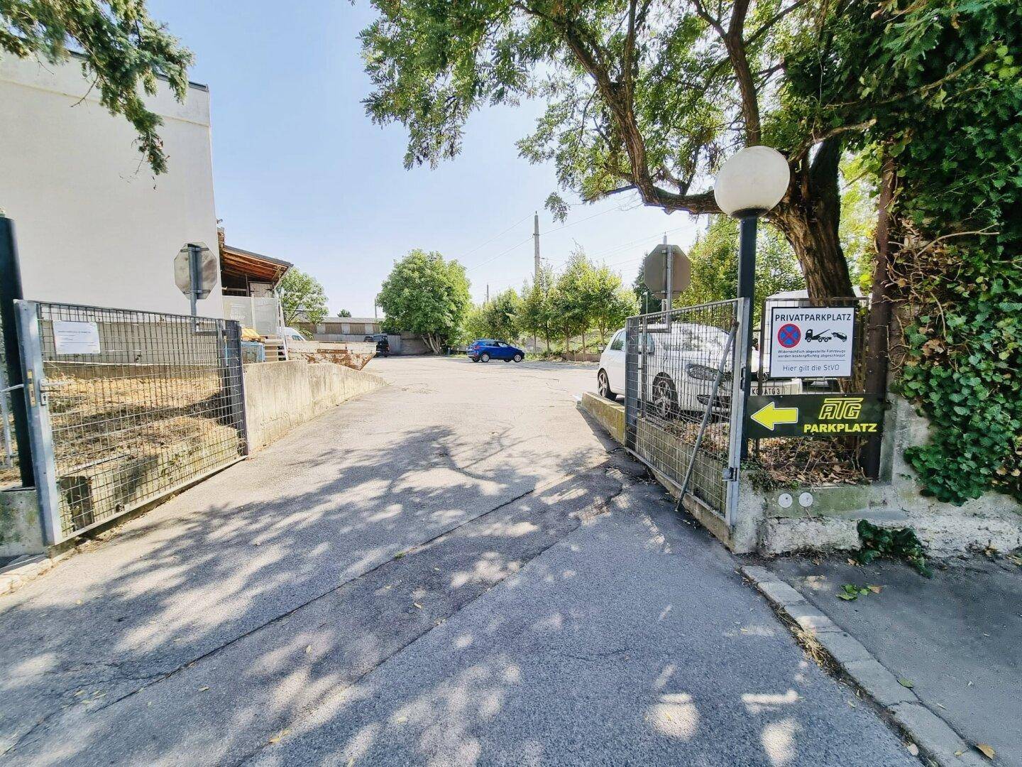 Einfahrt zum Privatparkplatz mit einem Schild und einem Pfeil, der den Weg zum AIG Parkplatz weist.
