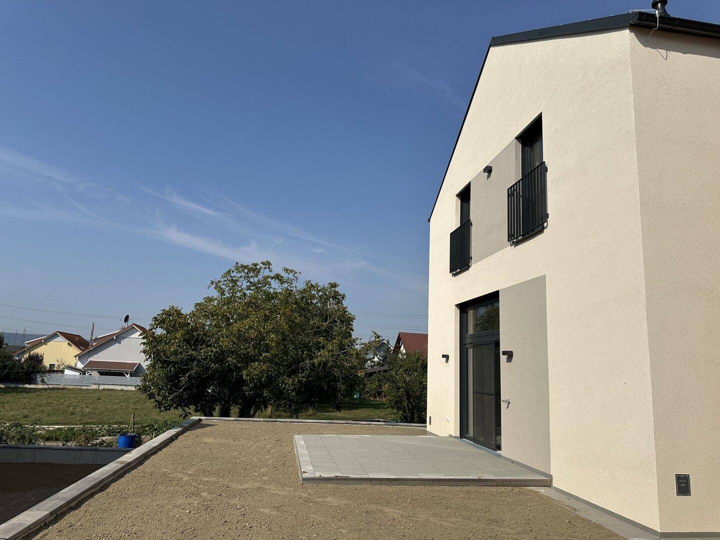 Seitenansicht eines modernen Reihenhauses mit Terrasse und weitem Blick in die ländliche Umgebung.
