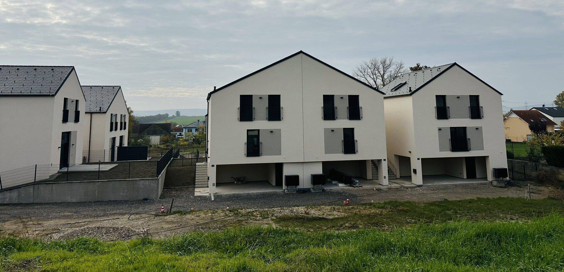 Mehrere moderne Reihenhäuser in einer ländlichen Umgebung mit Blick auf die weite Landschaft.