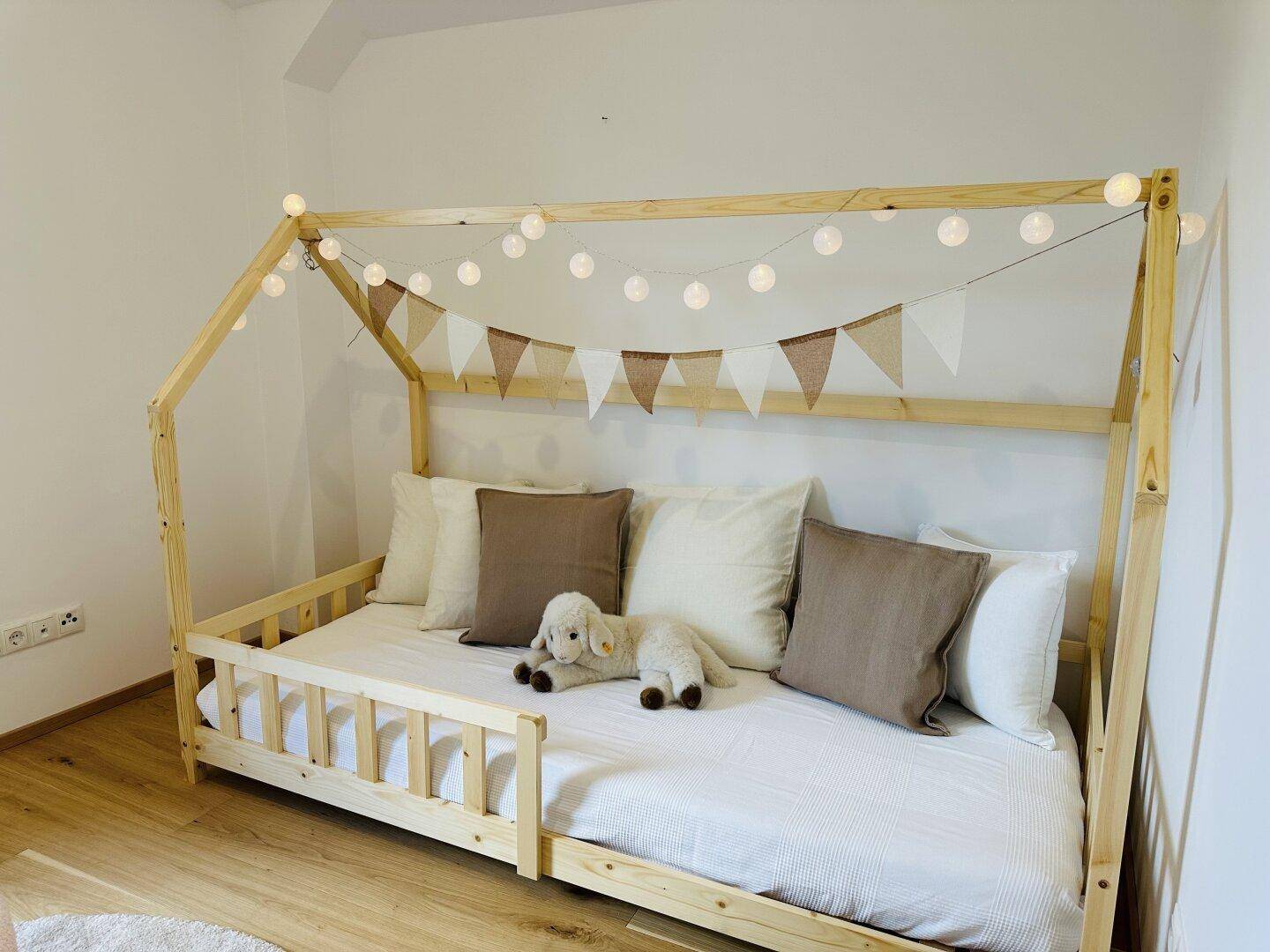 Kinderzimmer mit einem einzigartigen Hausbettrahmen und dekorativer Lichterkette.
