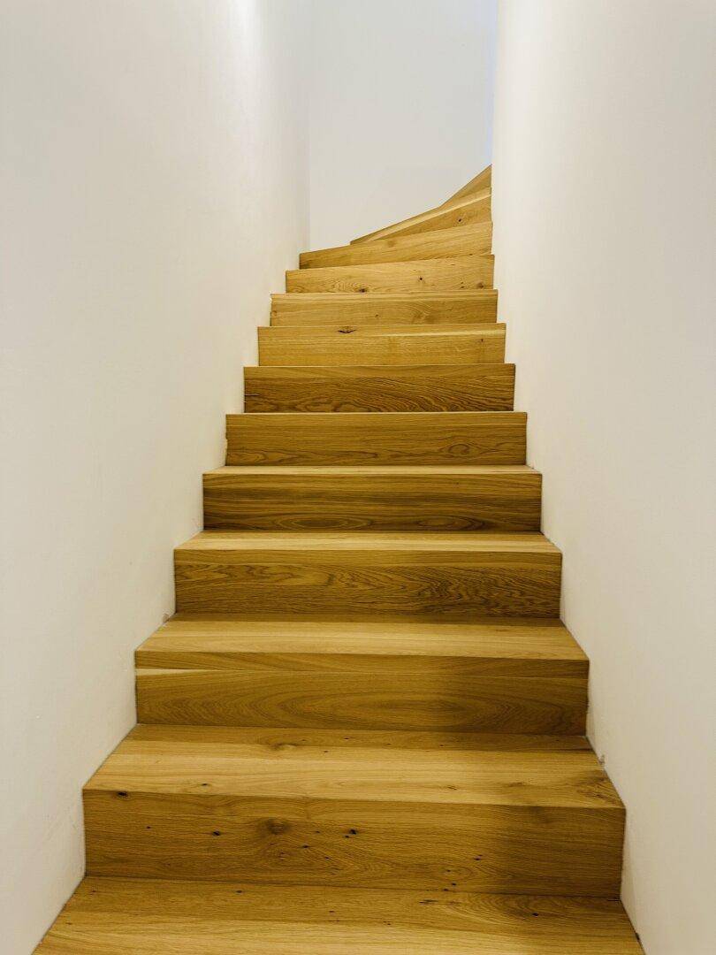 Elegante Holztreppe mit geschwungenen Stufen, die in die obere Etage führt.