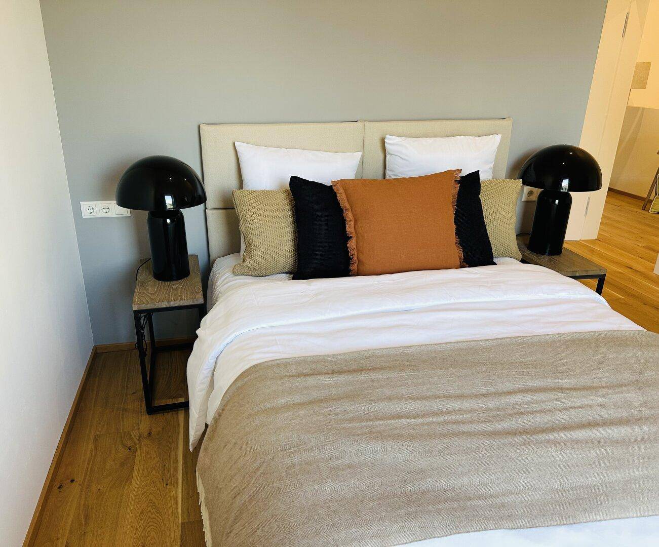 Gemütliches Schlafzimmer mit Doppelbett, Nachttischen und dekorativen Kissen.
