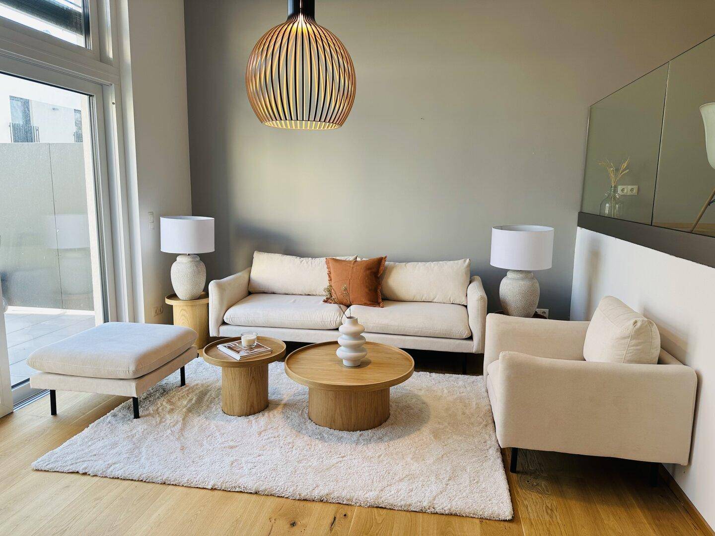 Helles Wohnzimmer mit modernem Mobiliar, Holzboden und Zugang zu einem Außenbereich.