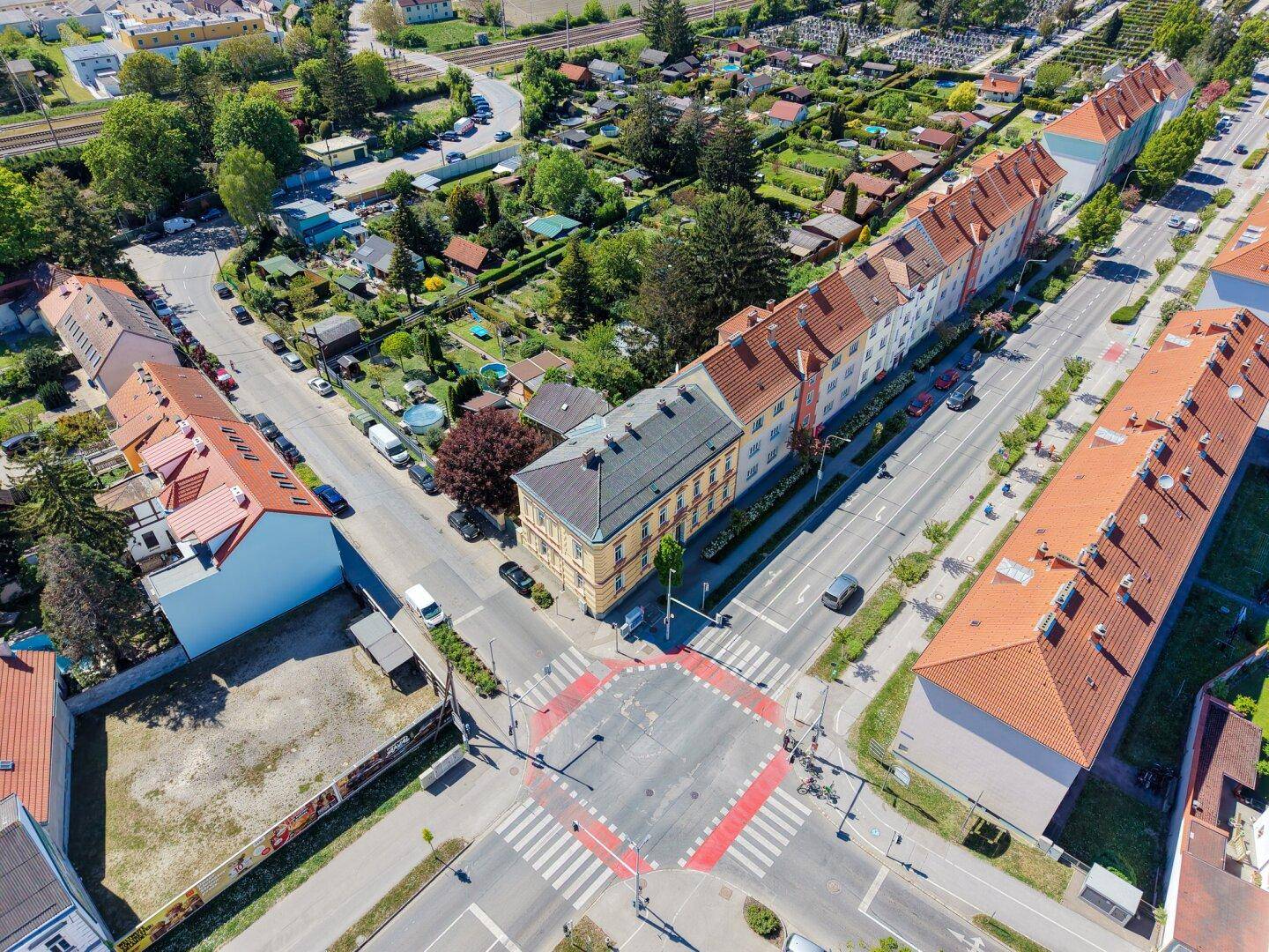 Weitläufige Luftaufnahme einer Wohngegend mit Straßen, Häusern und Gärten.