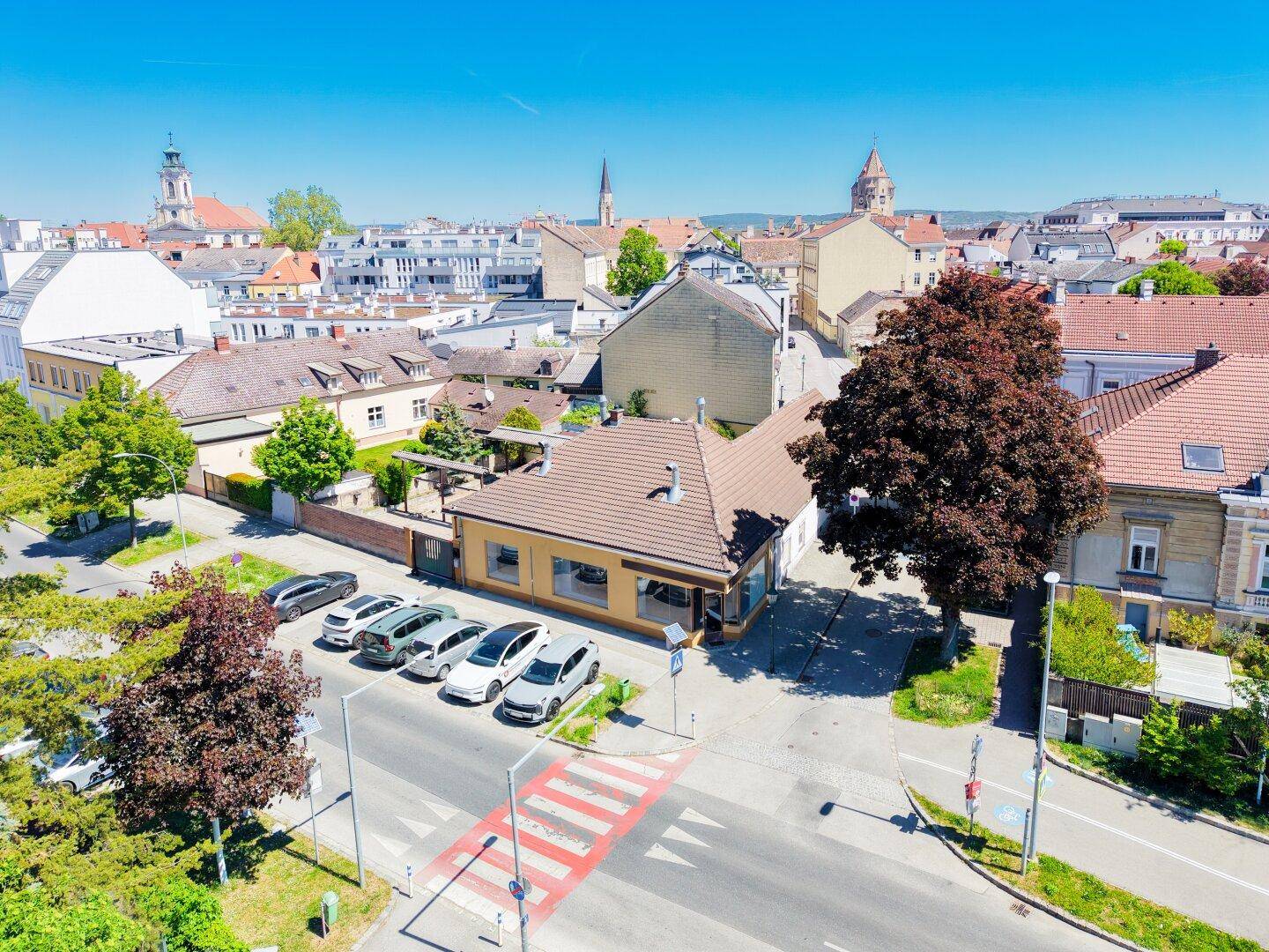 Luftaufnahme einer Stadtansicht mit historischen Gebäuden und einem Kirchturm am Horizont.