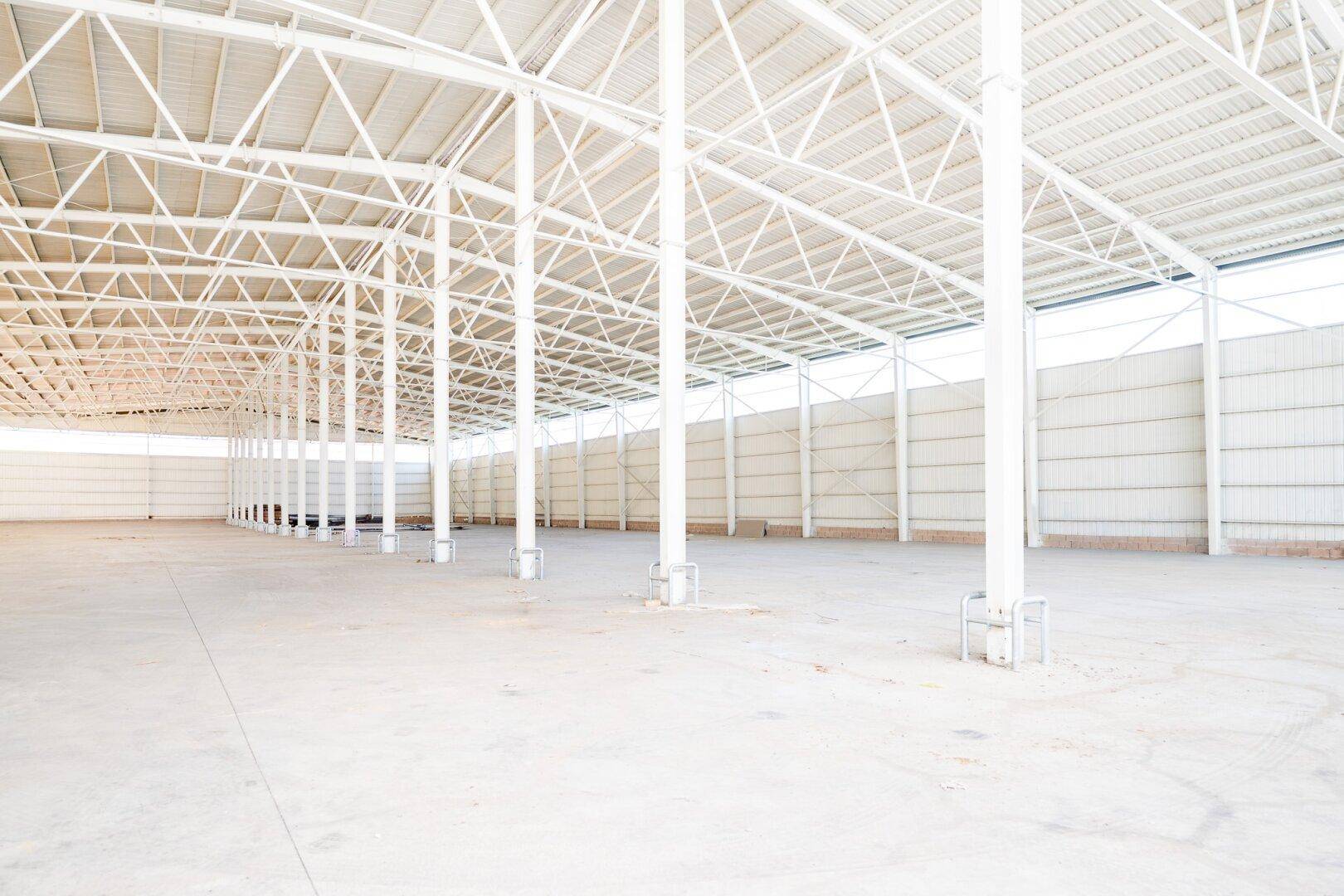 Weitläufige, leere Industriehalle mit vielen Stützpfeilern und heller Betonbodenfläche.