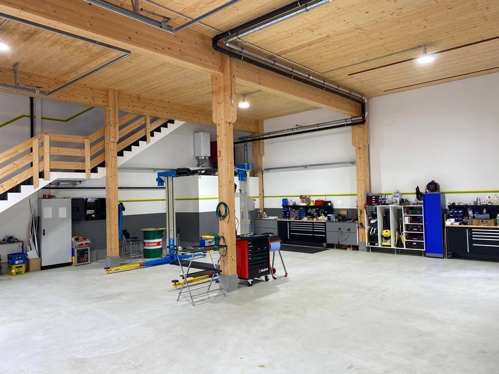 Geräumige Werkstatt mit Holzbalken, Betonboden und umfangreichen Arbeitsbereichen, gut ausgestattet.
