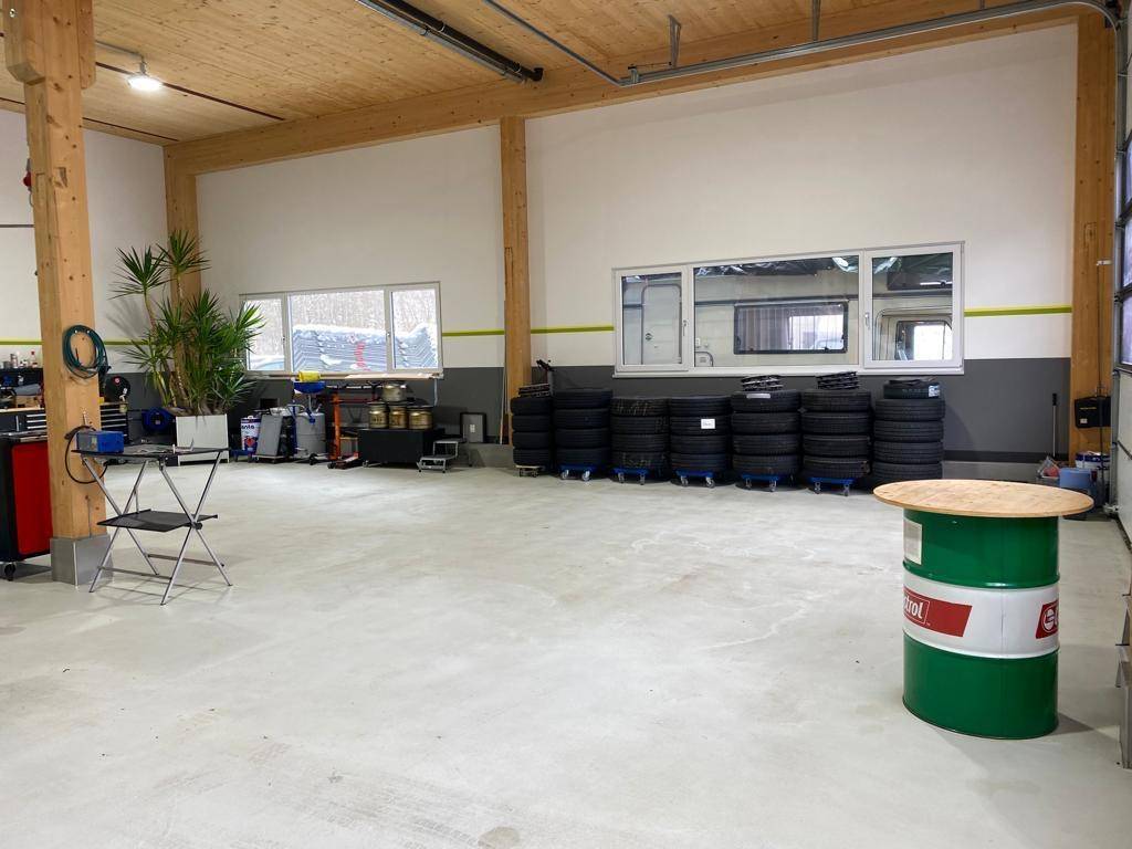 Werkstatt mit Reifenlager, Arbeitsbereich und großen Fenstern, bietet viel Platz.