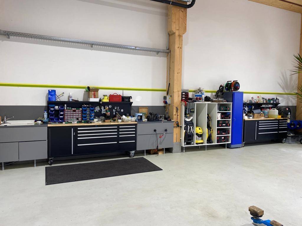 Blick von oben auf den Fahrzeuglift in der Werkstatt, umgeben von Arbeitsgeräten.