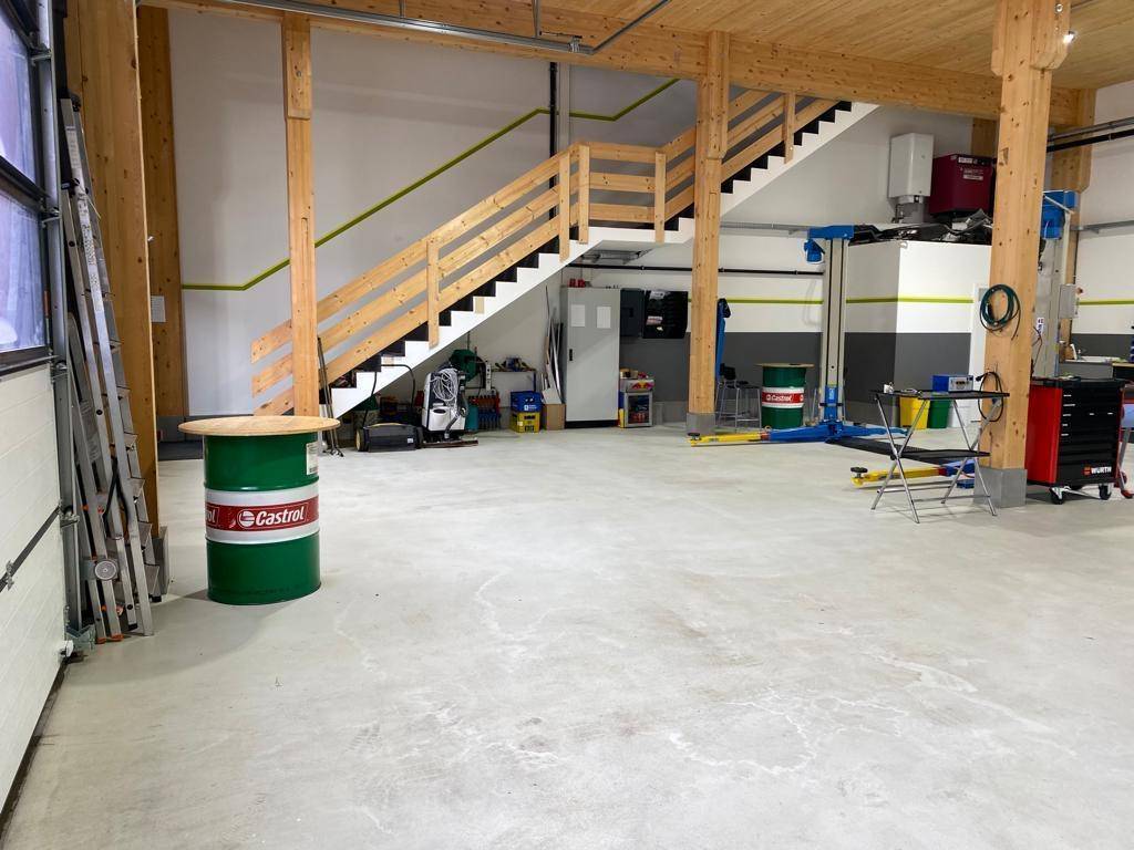 Werkstatt mit Holztreppe, Fahrzeuglift und großem Garagentor, vielseitig nutzbar.