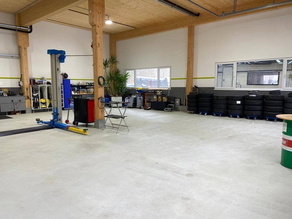 Werkstatt mit Reifenlager, Arbeitsbereichen und großen Fenstern, ideal für Fahrzeugservice.